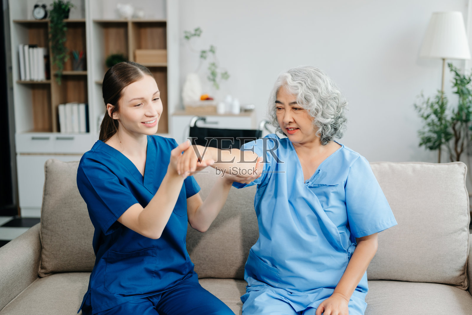 物理治疗师帮助老年妇女患者在运动中伸展手臂，在训练中纠正患者背部问题照片摄影图片