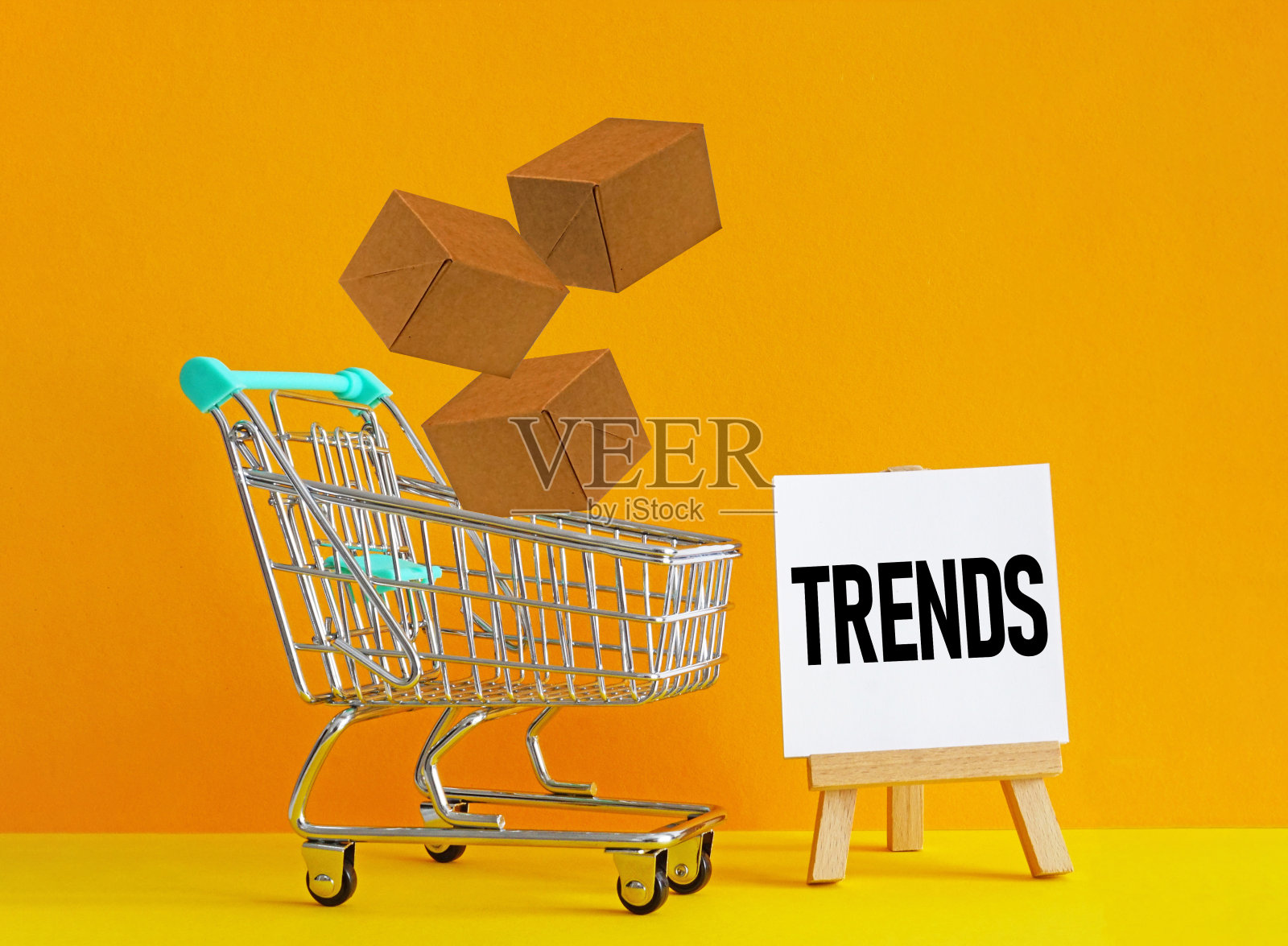 零售的趋势。电子商务零售购物趋势概念。购物车与黄色背景的盒子照片摄影图片