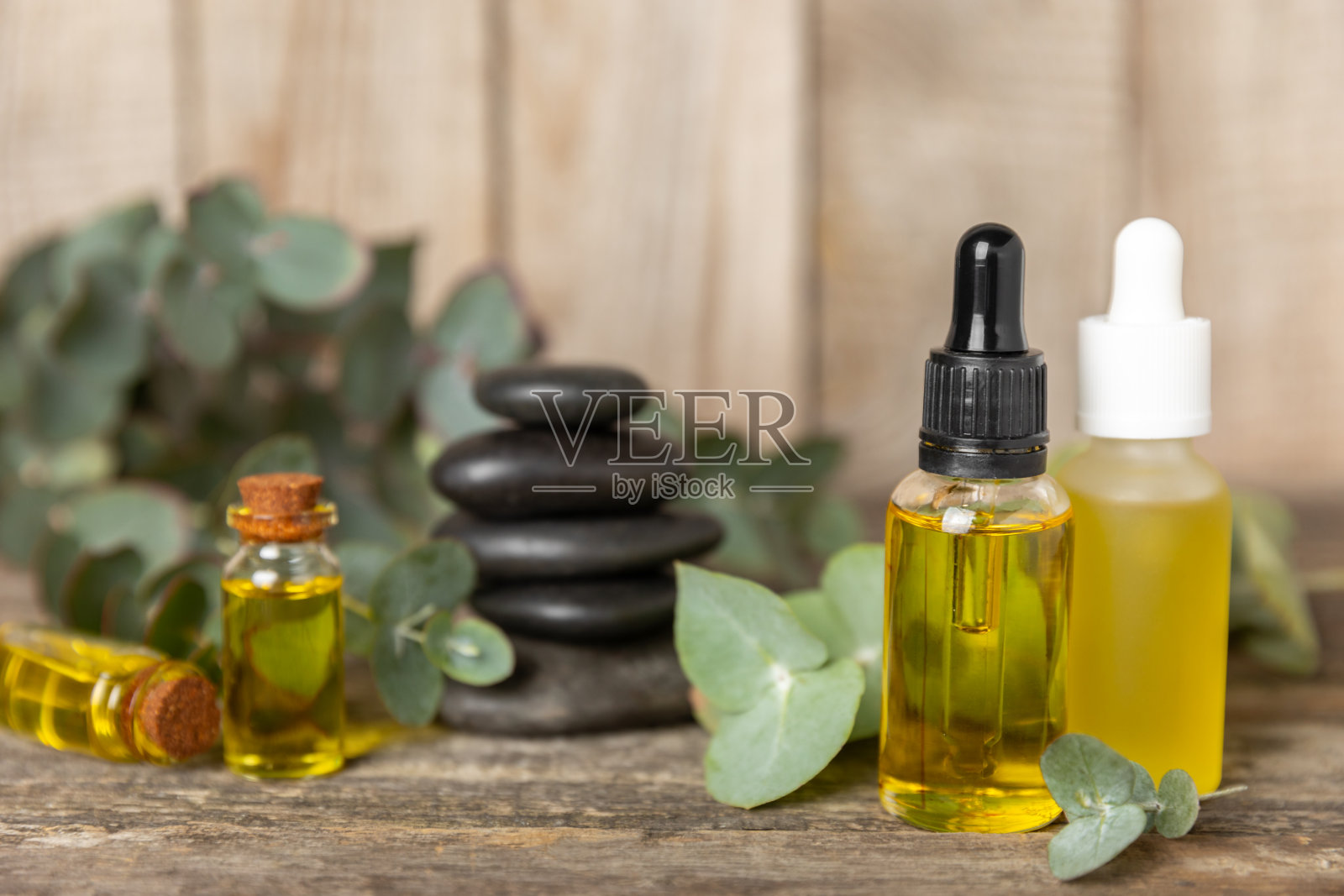 桉树精油在一个玻璃瓶子与绿色桉树叶子纹理木制背景。芳香疗法的概念。水疗中心。天然有机成分，用于化妆品和身体护理。本空间照片摄影图片