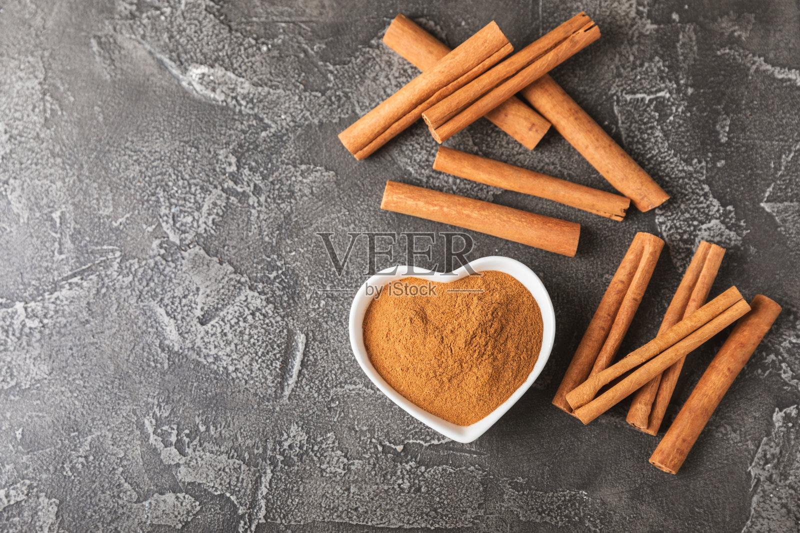 肉桂棒在有纹理的木制背景。肉桂卷。用于烘焙、甜点和饮料的辛辣香料。芳香的肉桂粉。肉桂粉特写。放文字的地方。本空间照片摄影图片