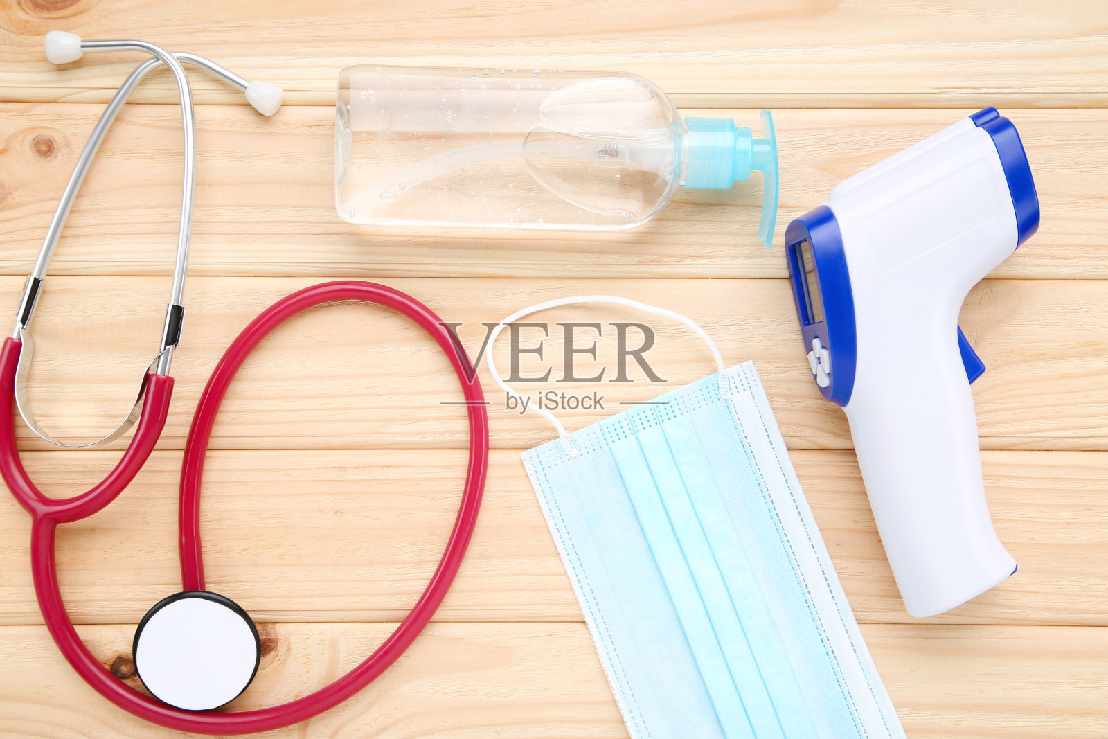 木制背景红外温度计，配有医用口罩、消毒瓶和听诊器照片摄影图片
