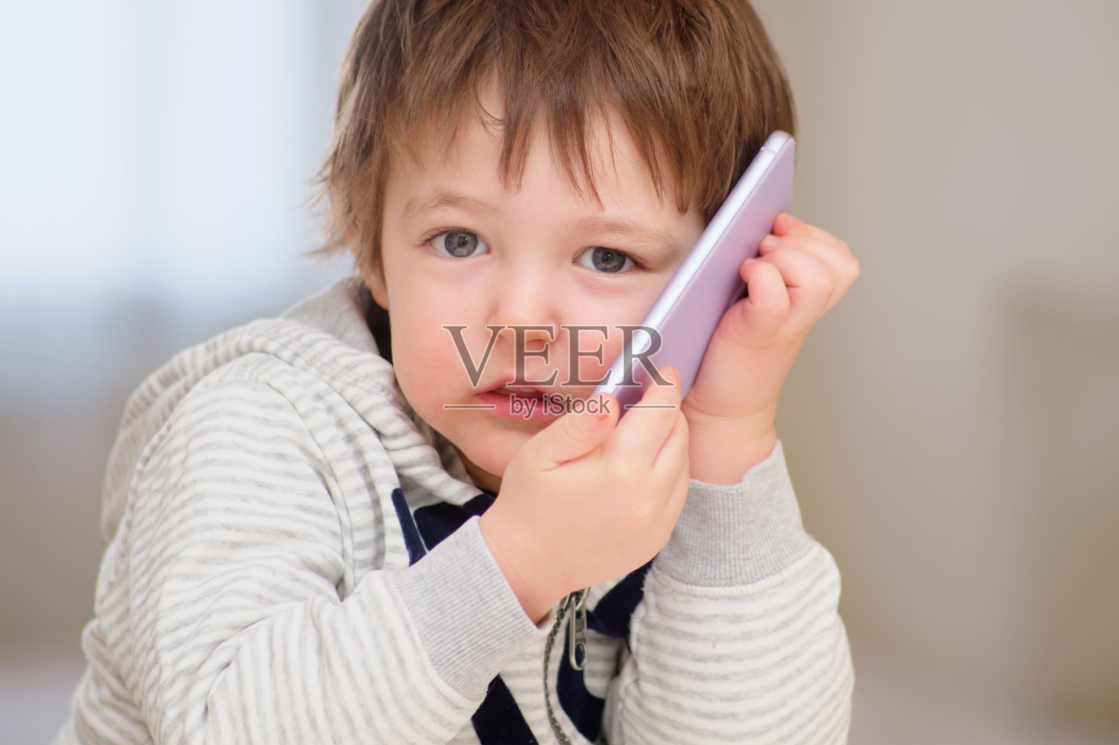 一个害怕的婴儿正在用手机说话。一个悲伤的孩子在打电话。两岁儿童照片摄影图片