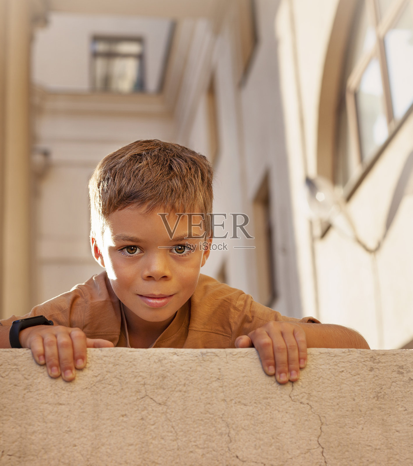 一个可爱的男孩靠在街上的墙上的肖像照片摄影图片