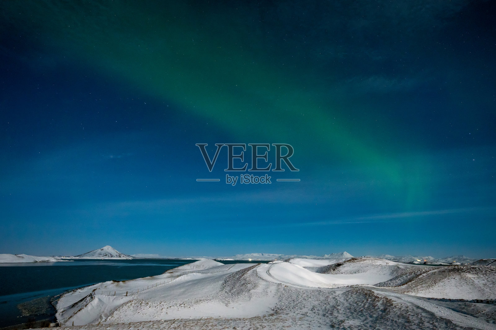 北极光是冰岛天空中令人惊叹的自然奇观。夜景随着绿光在美丽的舞姿映得像一面镜子照片摄影图片