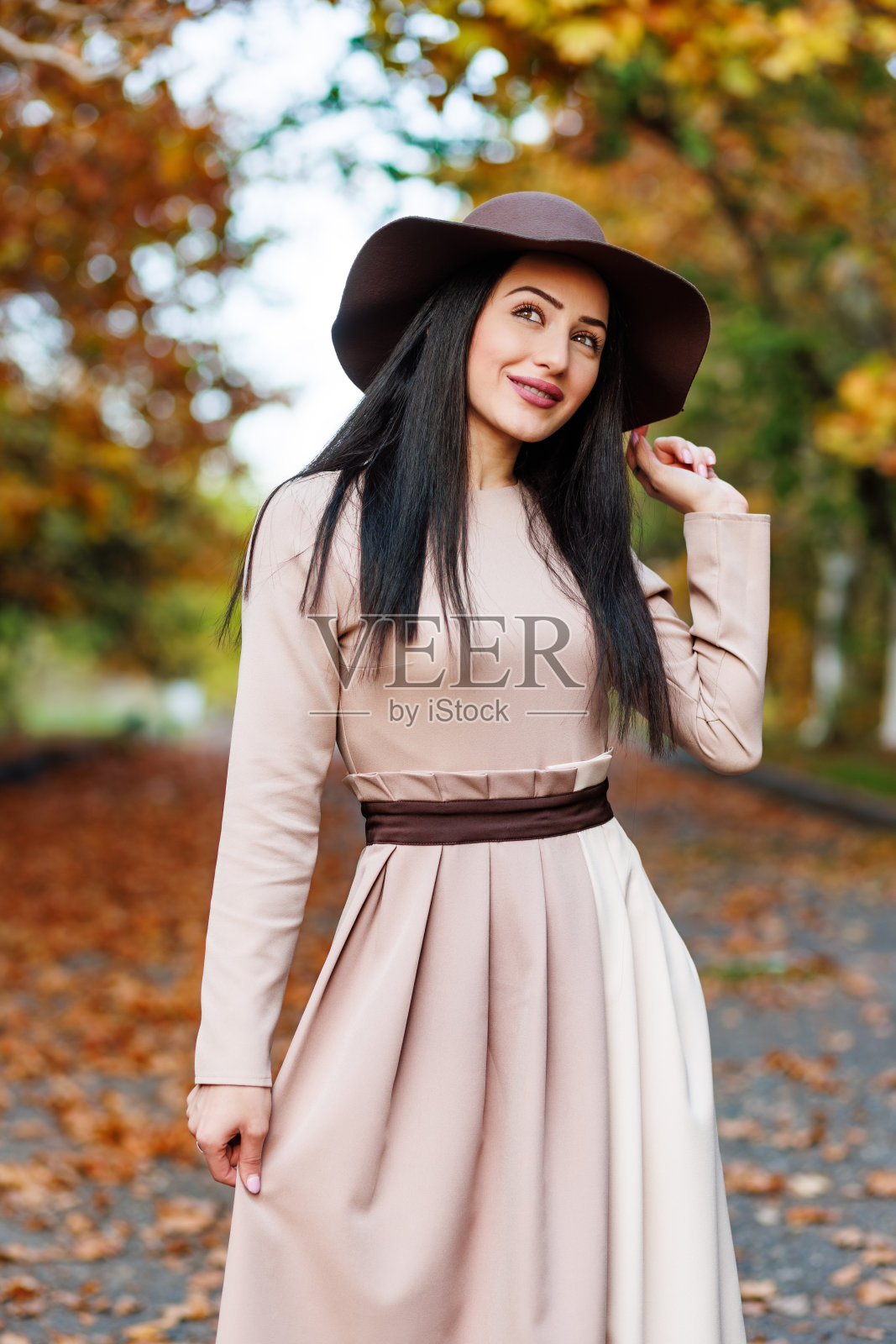 甜美的年轻女子，带着闪亮的眼睛和宽边帽，在充满活力的秋天公园里摆姿势拍照照片摄影图片