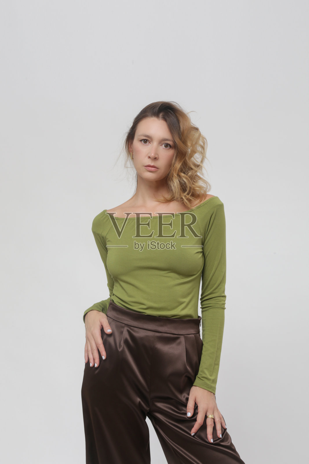 一系列的工作室照片的年轻女模特穿着舒适的基本装，绿色粘胶合身的衬衫和棕色裤子照片摄影图片