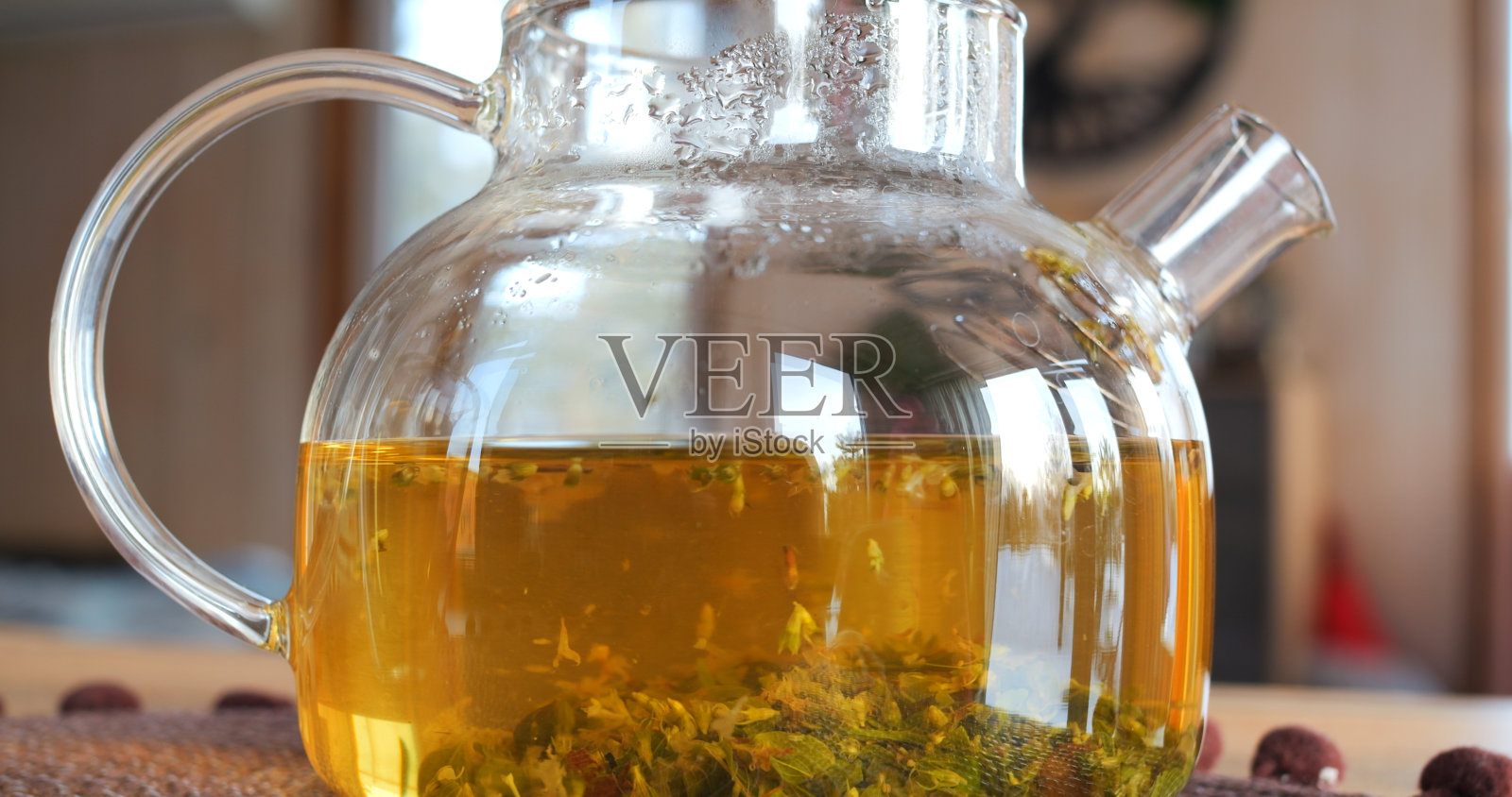 在桌子上的玻璃茶壶里泡制草药的特写。令人着迷的芳香草药混合物，因为它酿造，丰富的时刻与自然的善良。草药饮料的镇静气氛照片摄影图片