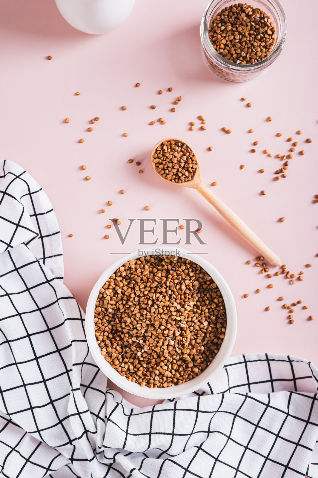 白色碗与生的全谷物荞麦在粉红色的背景顶部和垂直视图照片摄影图片