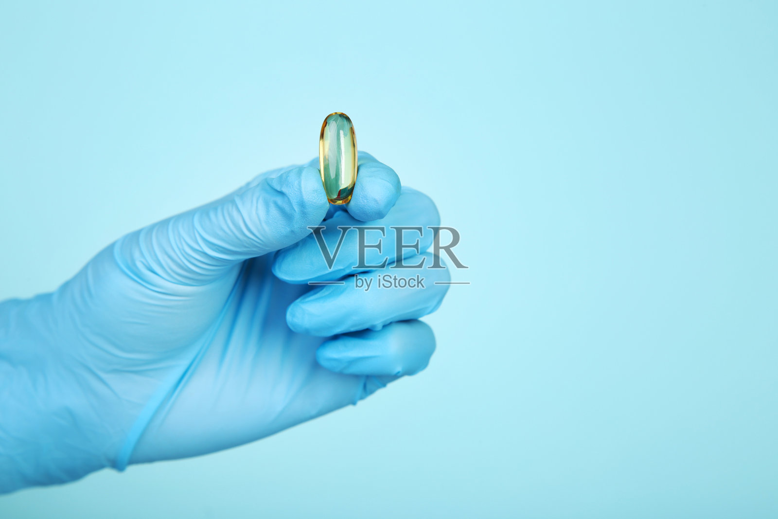 医生手戴手套，拿着蓝色背景的胶囊照片摄影图片