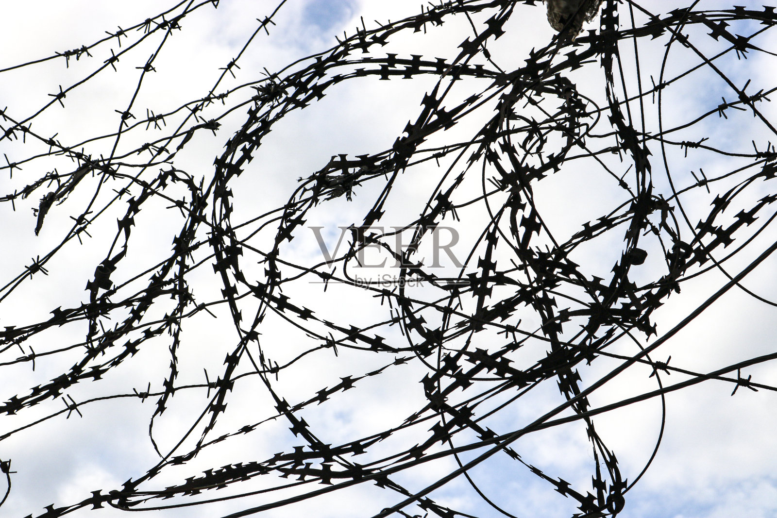 倒刺铁丝对着天空的特写。照片摄影图片