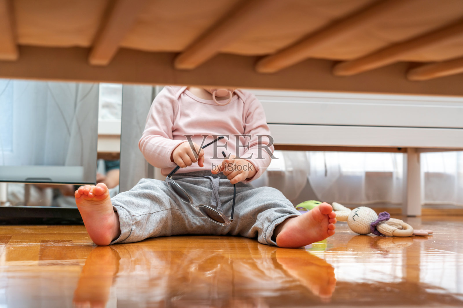 婴儿嘴里含着奶嘴，戴着墨镜从婴儿床下面看照片摄影图片