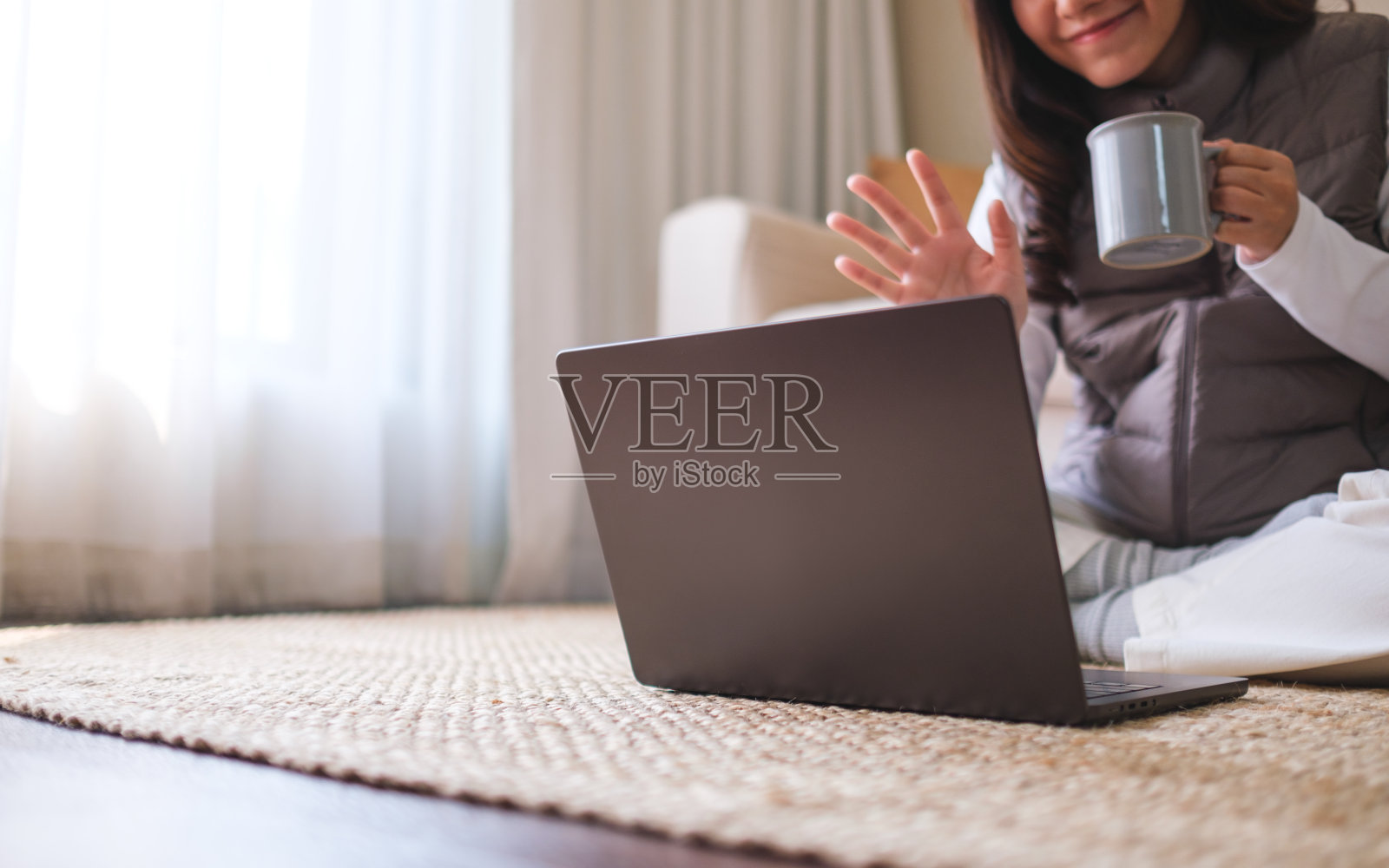 一个年轻女子在家里一边喝咖啡一边用笔记本电脑进行视频通话的特写照片摄影图片