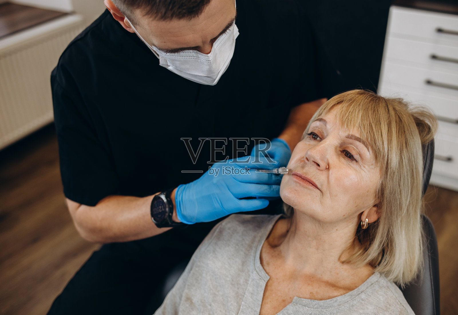 美容，整形外科和美容概念-高级妇女和外科医生的手与注射器在蓝色背景照片摄影图片