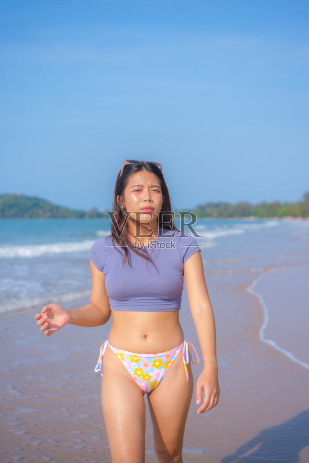 年轻的亚洲女子穿着泳衣走在沙滩上照片摄影图片