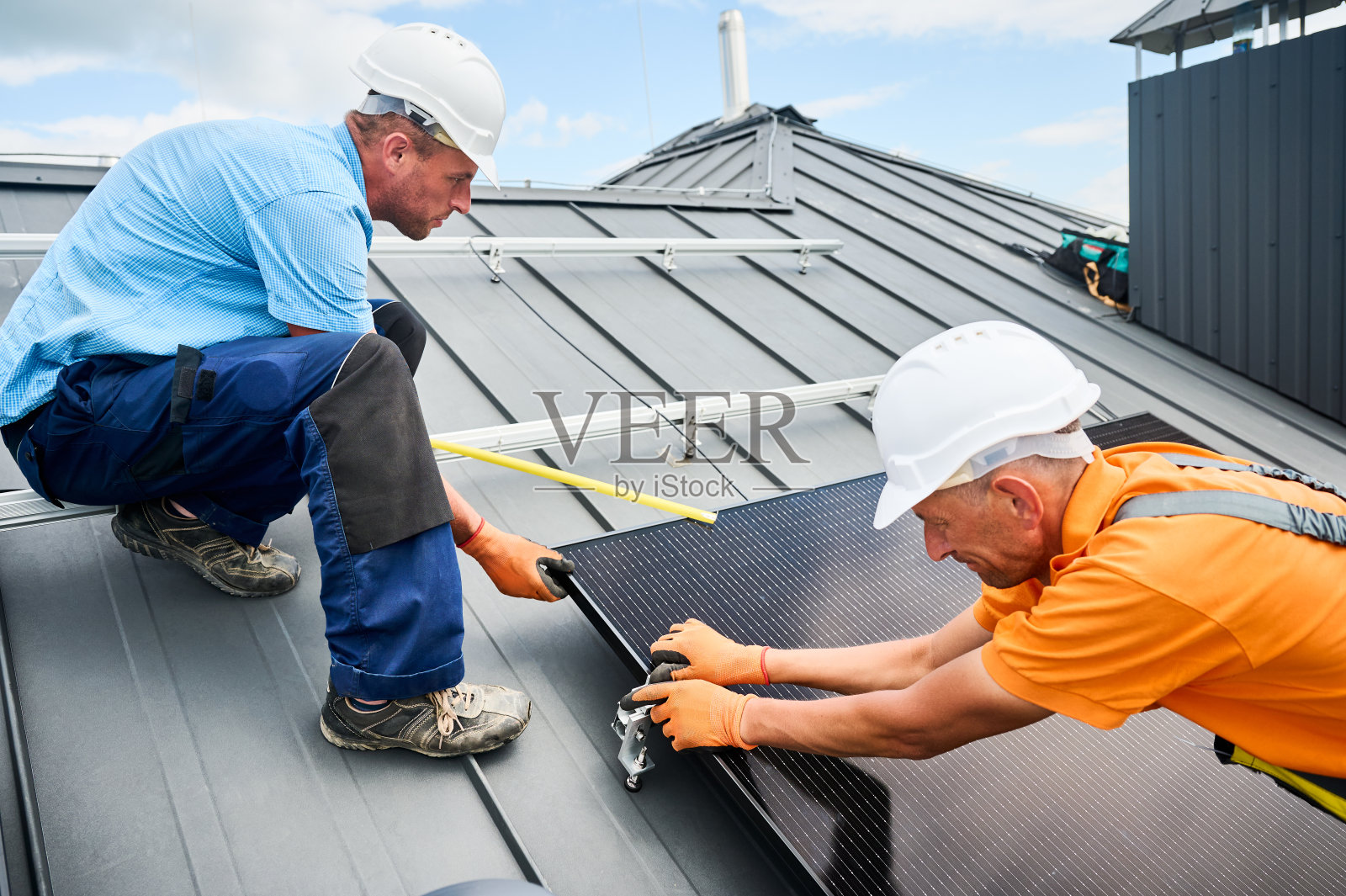 工人用内六角键在屋顶上建造光伏太阳能电池板系统。照片摄影图片