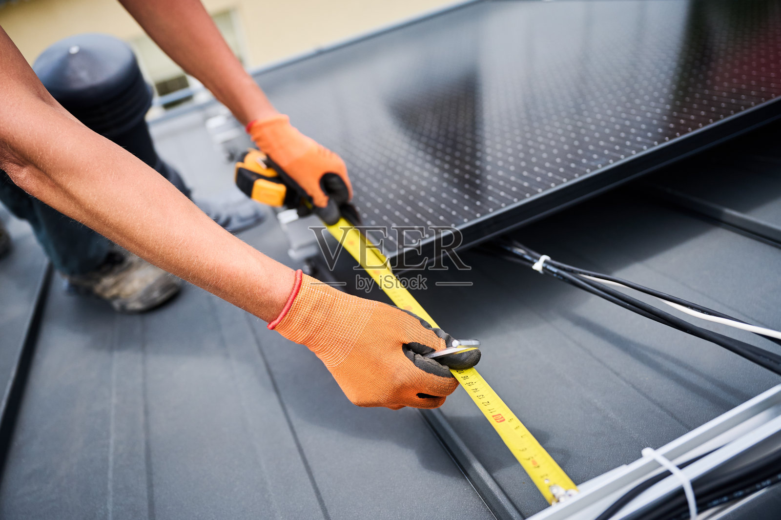 工人在搭建光伏太阳能电池板系统，用尺子测量安装设备。照片摄影图片