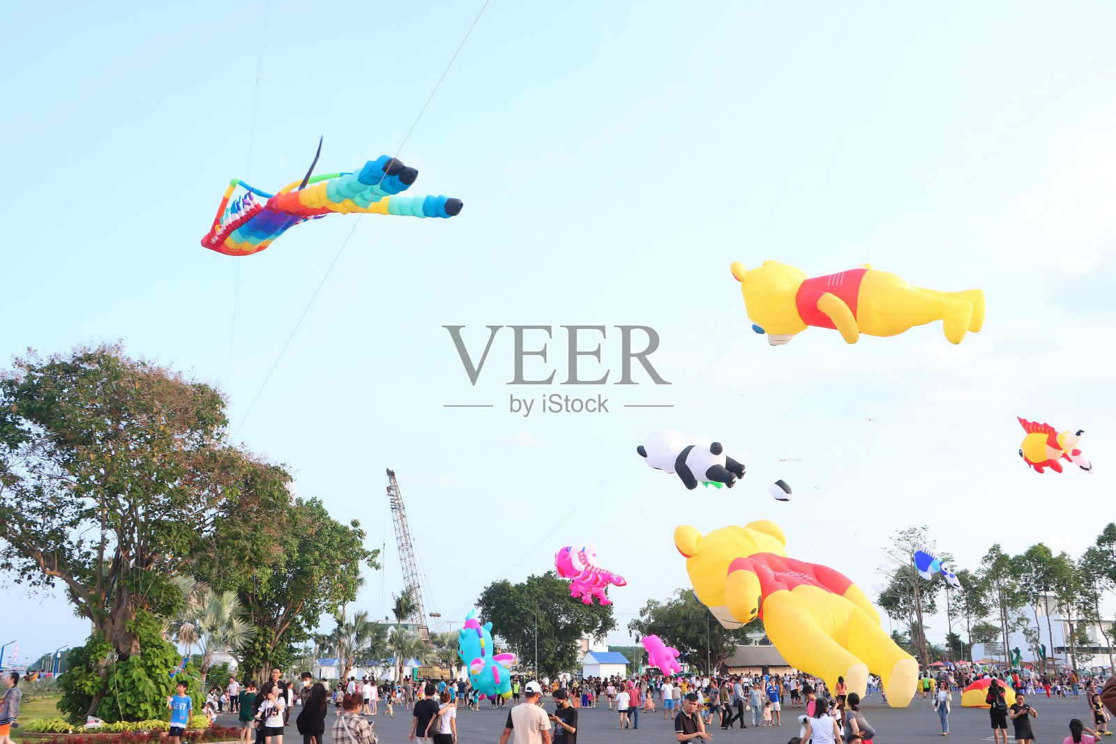 在越南湄公河三角洲，人们拿着五颜六色的风筝，背景是湛蓝的天空，这是一种很受欢迎的户外玩具。快乐的童年时光。照片摄影图片