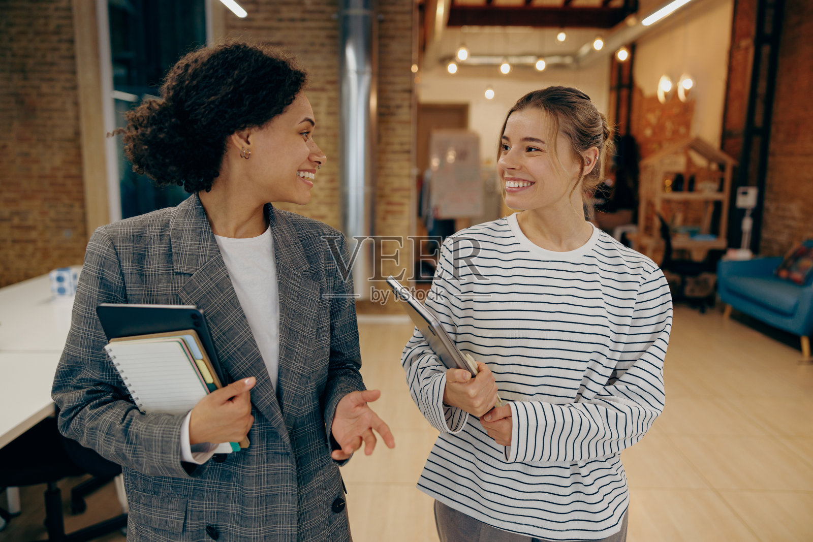 微笑的女同事在工作场所谈笑，享受休闲时光。企业文化理念照片摄影图片