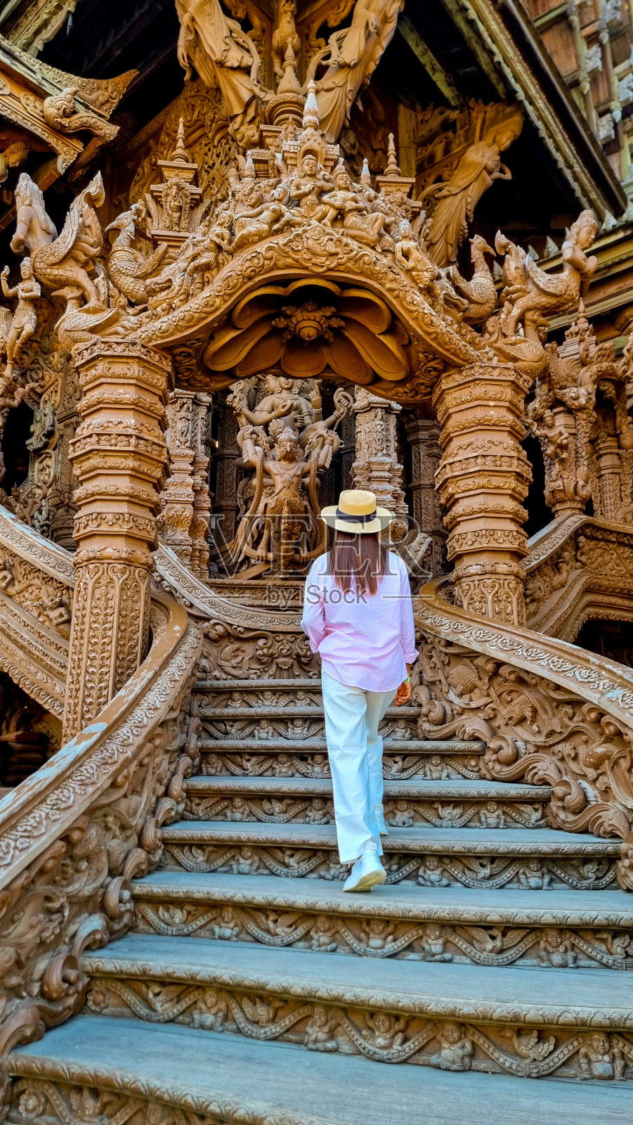 一个戴着草帽的神秘女人优雅地走下楼梯，目的明确，体现了优雅和冒险照片摄影图片