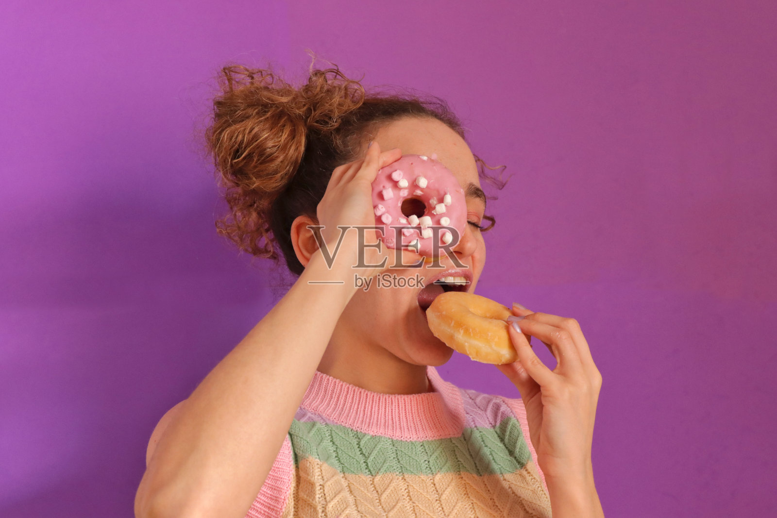 被甜甜圈塞进眼睛的年轻白种女人照片摄影图片