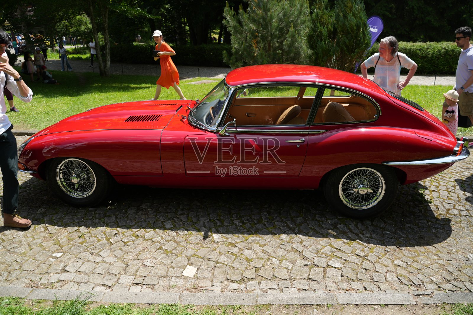 红色经典捷豹e型停在鹅卵石路上，周围都是人照片摄影图片