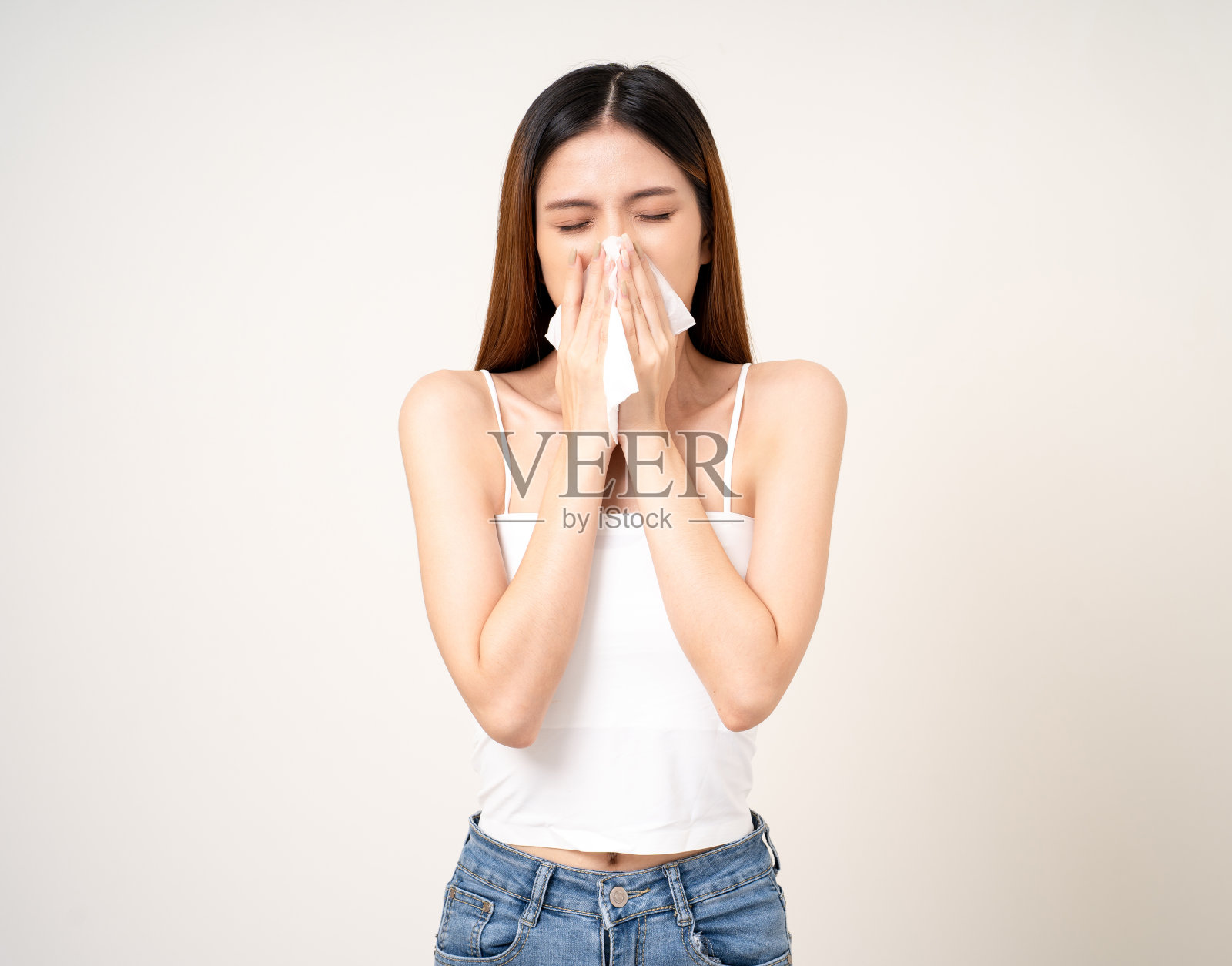 患有流鼻涕和高烧。寒热概念。美丽的年轻亚洲患病妇女的肖像在孤立的白色背景被围巾包裹打喷嚏。照片摄影图片