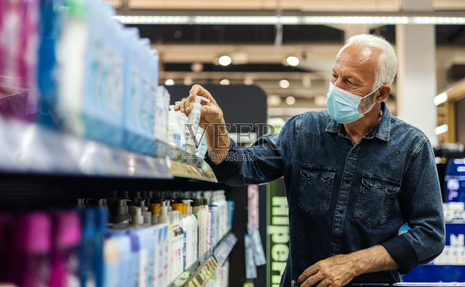 一名男子在超市戴防护口罩，手持美容产品。概念，疾病，病毒，过敏，空气污染。预防空气中冠状病毒或新冠病毒的细菌感染。照片摄影图片