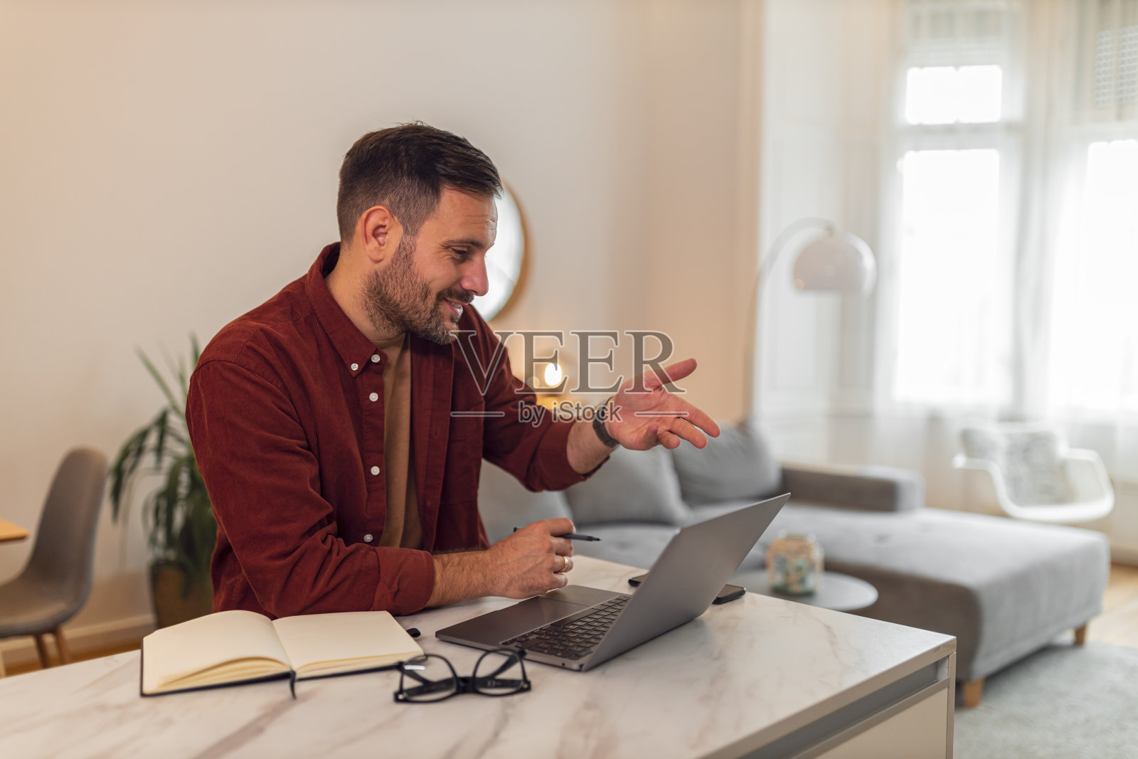 一个努力工作的年轻成年商人在家工作时用笔记本电脑与客户进行视频通话照片摄影图片