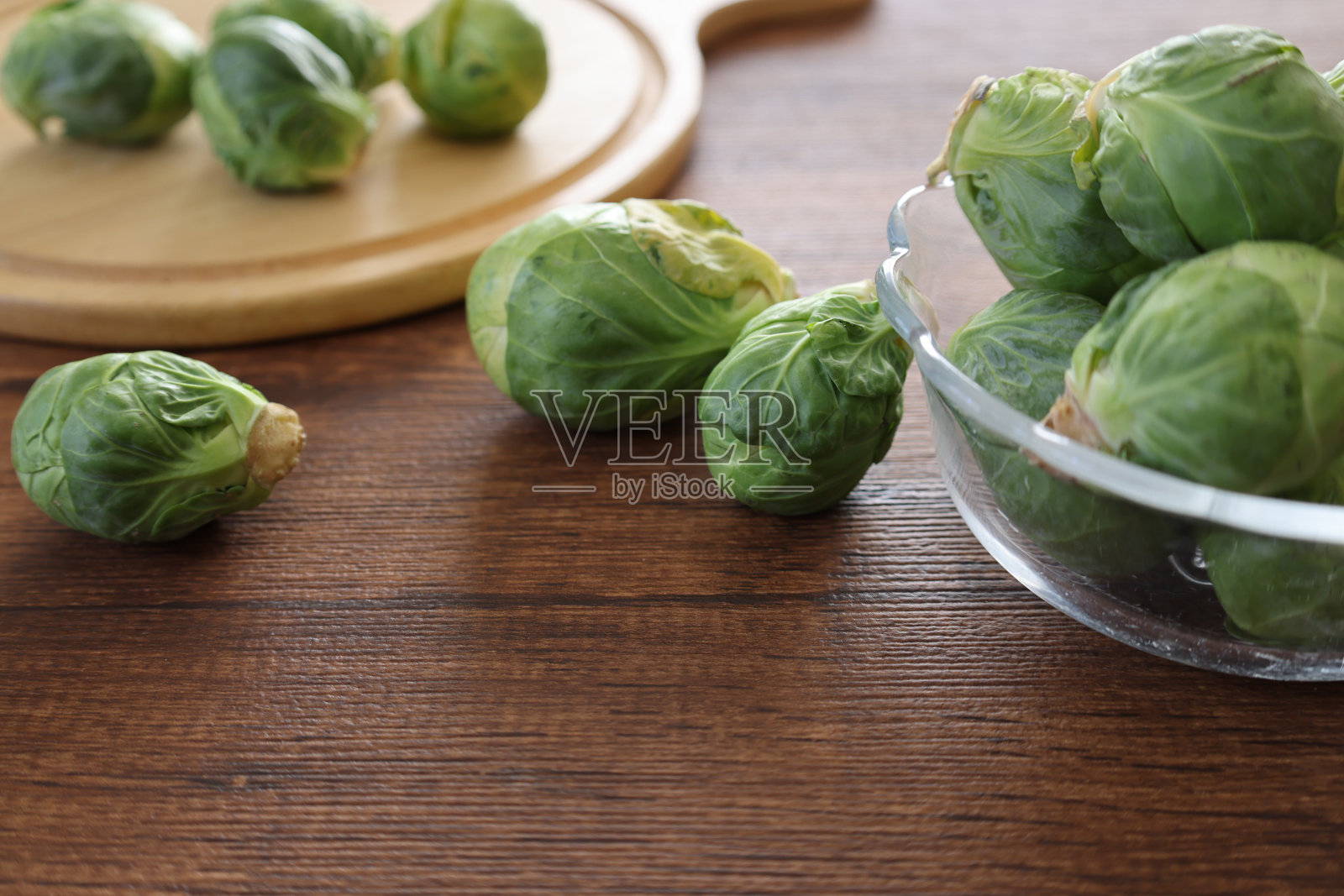 球芽甘蓝放在木桌上的玻璃碗里。照片摄影图片