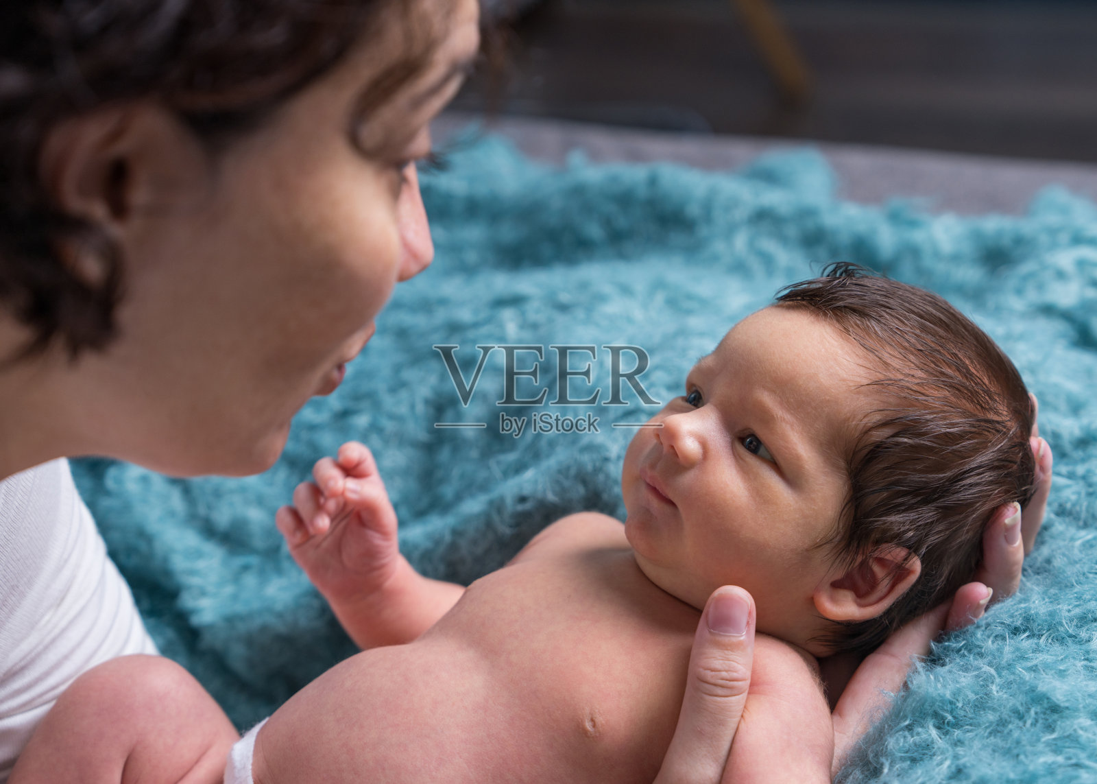 一位慈爱的母亲在家照顾她刚出生的婴儿。明亮的肖像，一个快乐的母亲抱着一个孩子在她的怀里。母亲拥抱她的小儿子。照片摄影图片