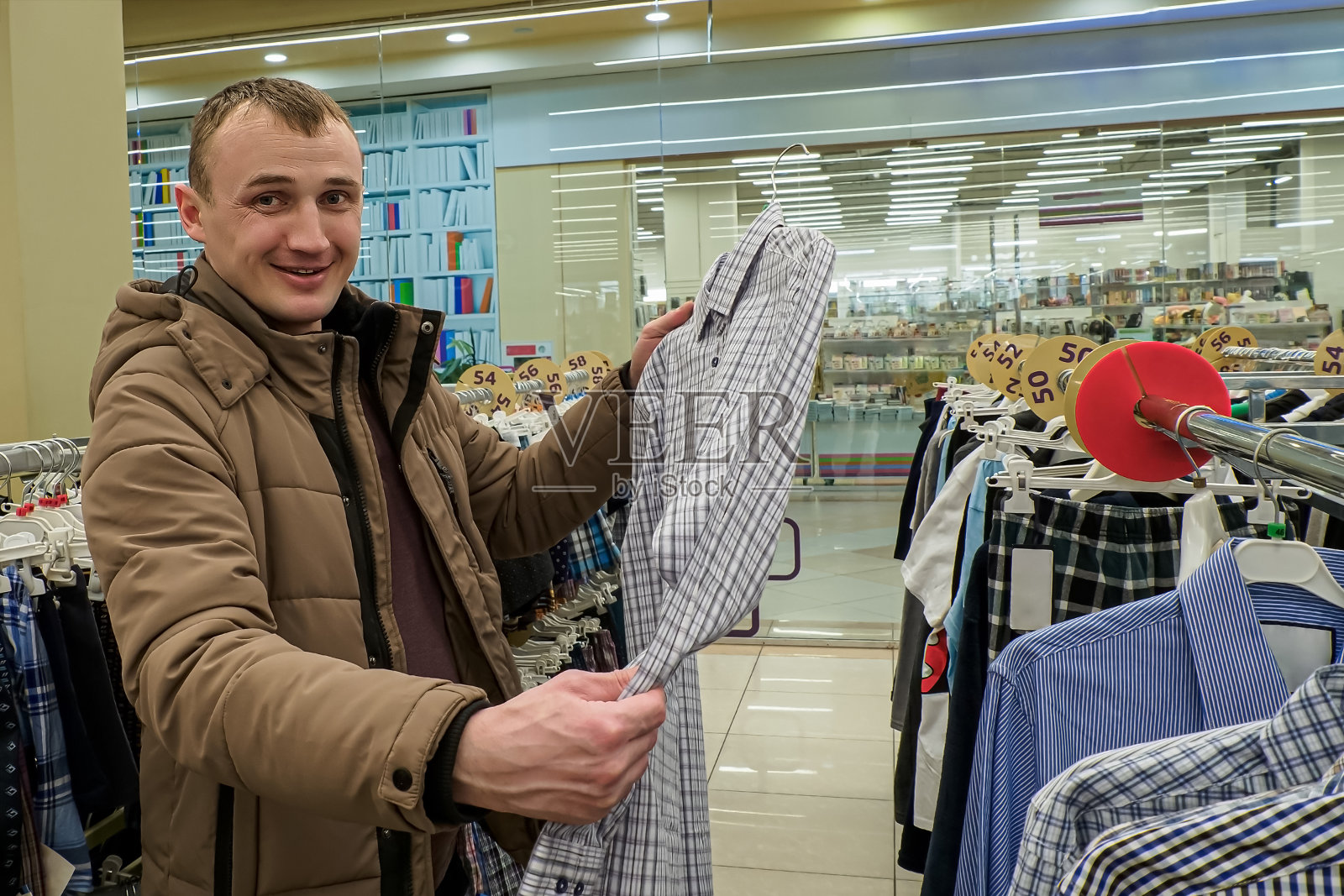 一个面带微笑的男人在挑选衬衫。轻便的衣服。服装店。纺织工业。零售贸易照片摄影图片