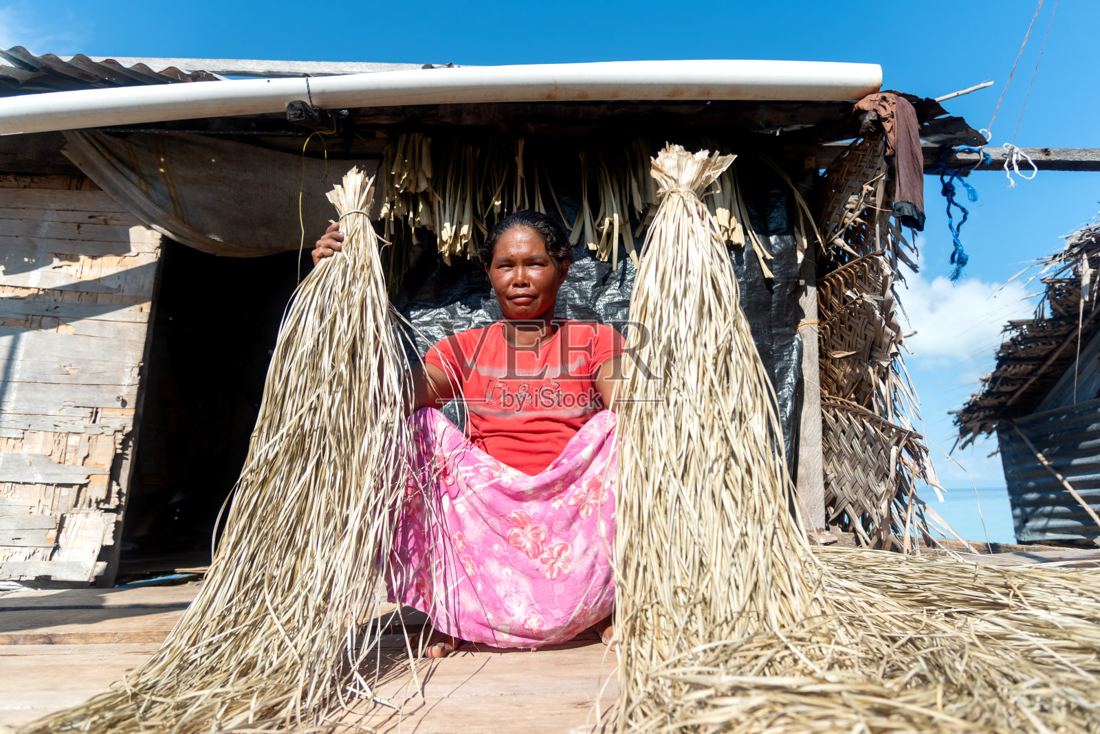巴瑶族妇女拿着一根干松木或香豆，准备做传统的垫子照片摄影图片