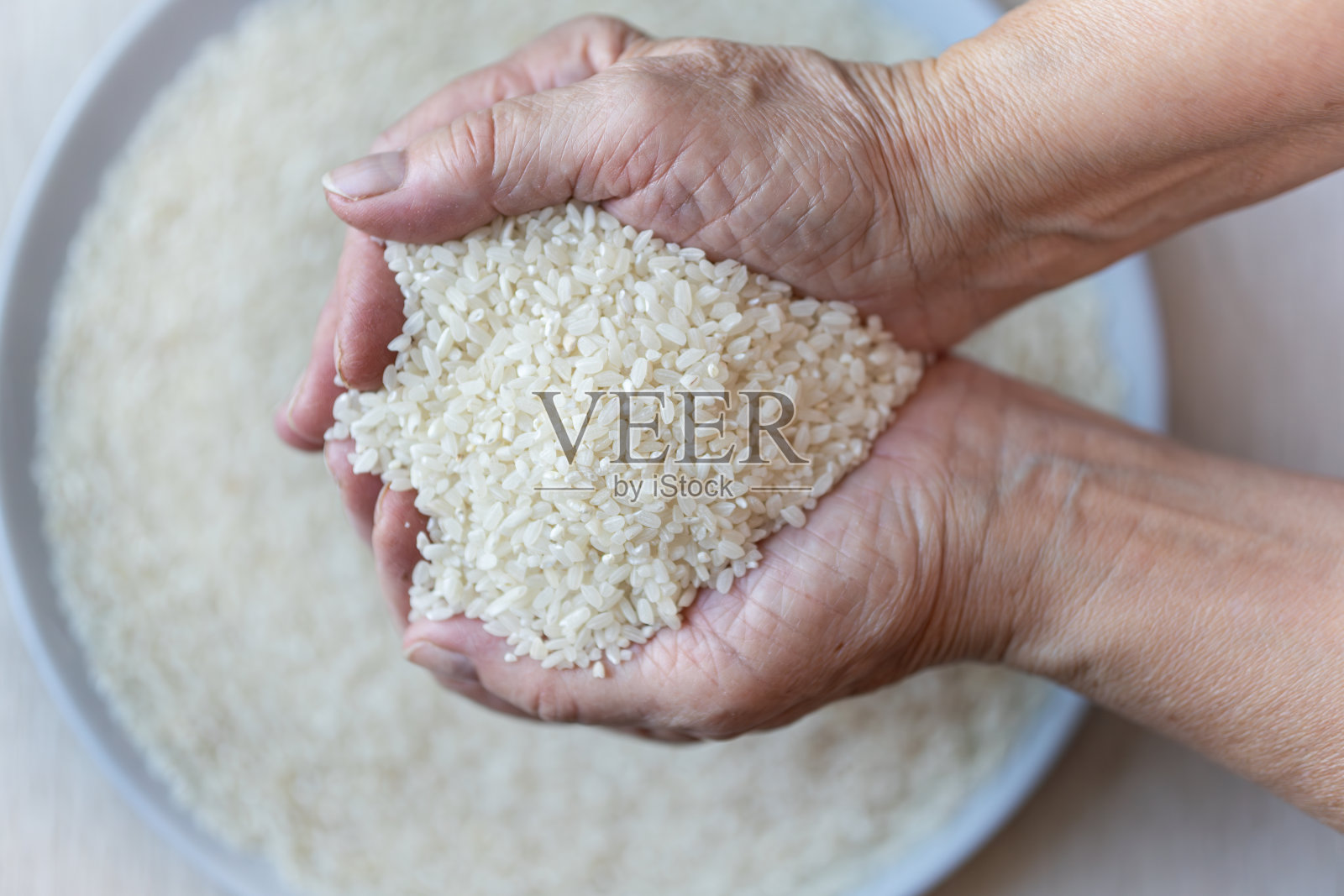 女人手中捧着茉莉花大米，大米从手中飘落，健康有机的理念。俯视图照片摄影图片