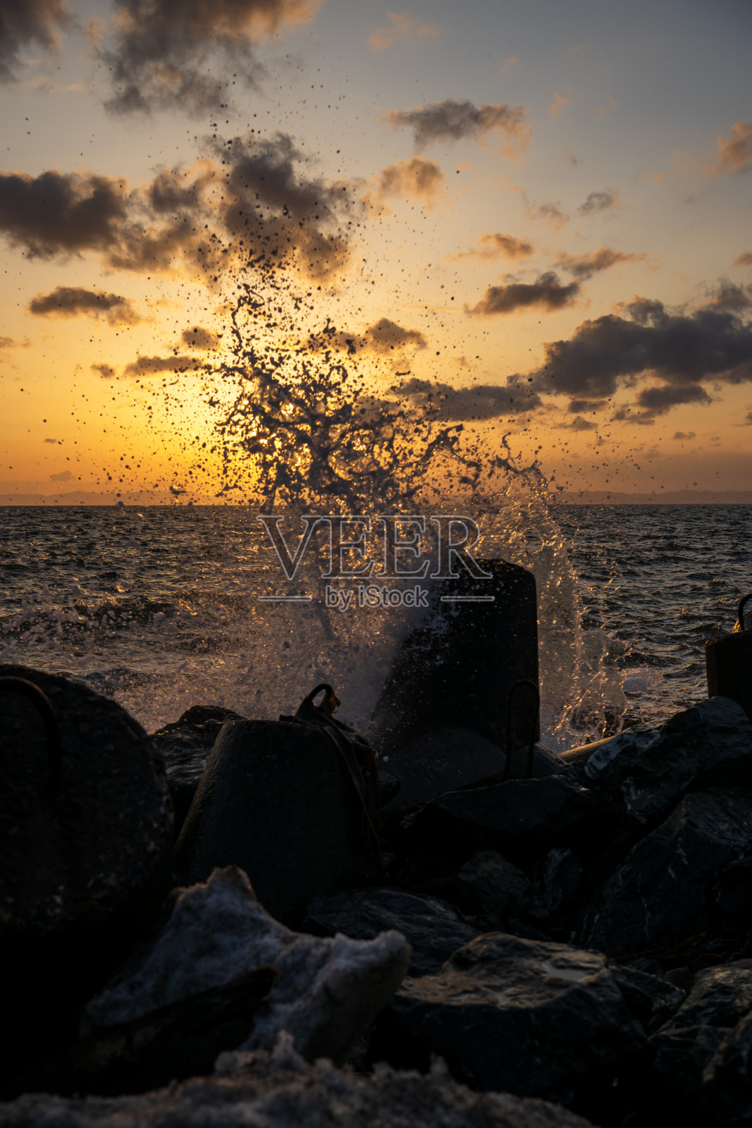 日落时海上防波堤上的水花照片摄影图片