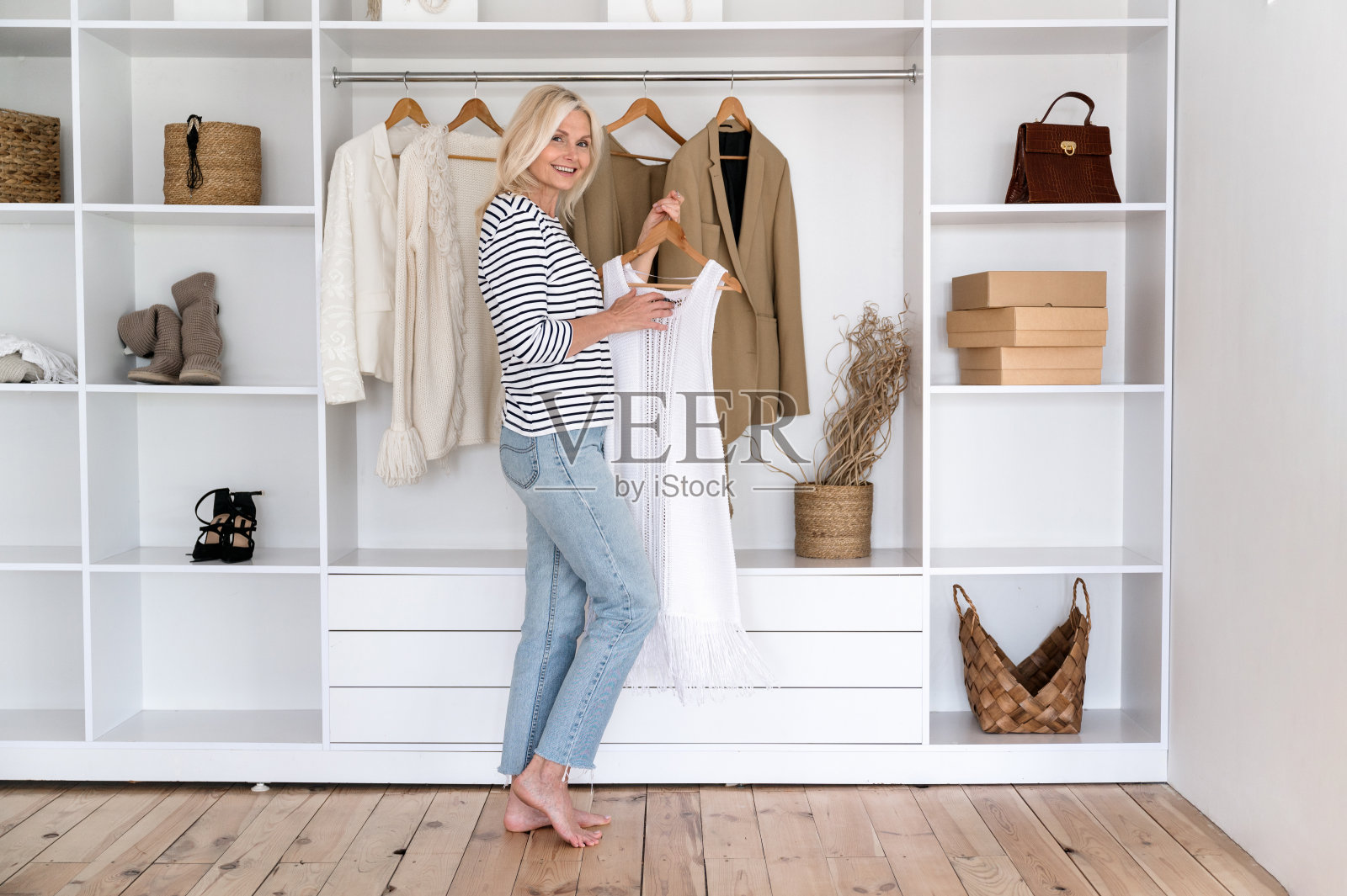 面带微笑的中年妇女，衣架在敞开的壁橱旁照片摄影图片