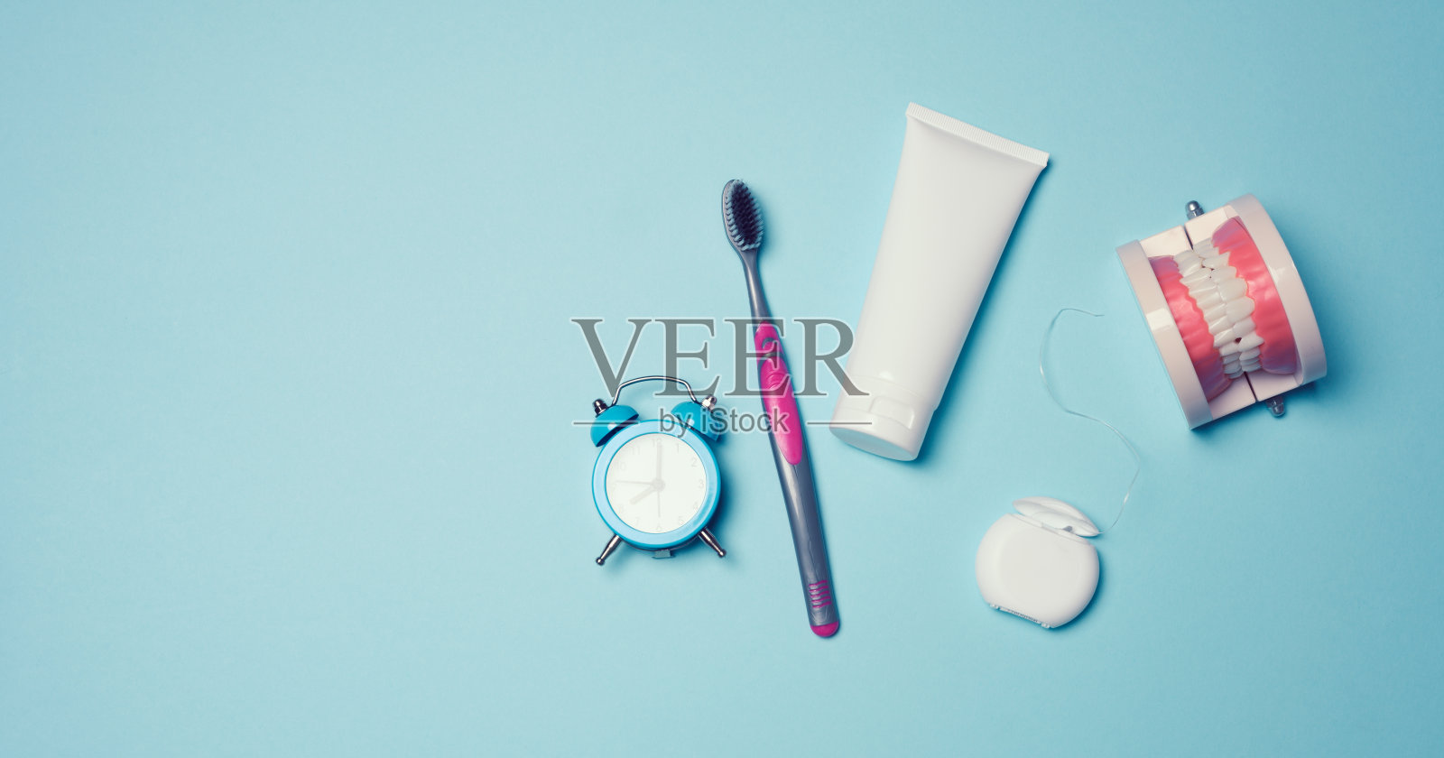 在蓝色的背景上，一个人的下巴，白色的牙齿，牙线和牙膏的模型照片摄影图片