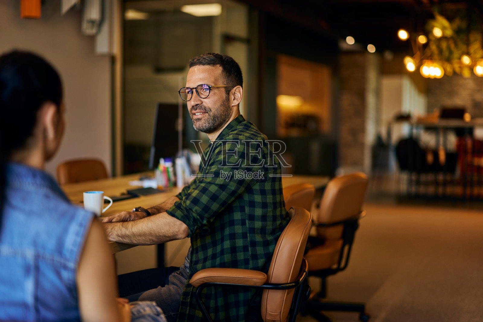 两个同事坐在一起聊天。照片摄影图片