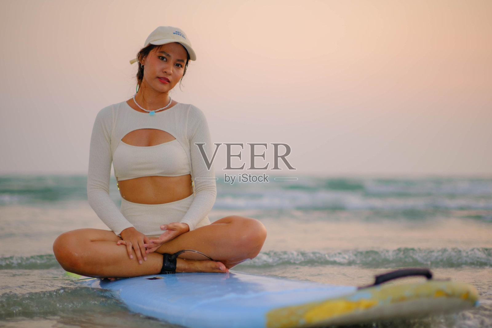 美丽的年轻亚洲女子坐在冲浪板上在海上度假看起来很开心。照片摄影图片