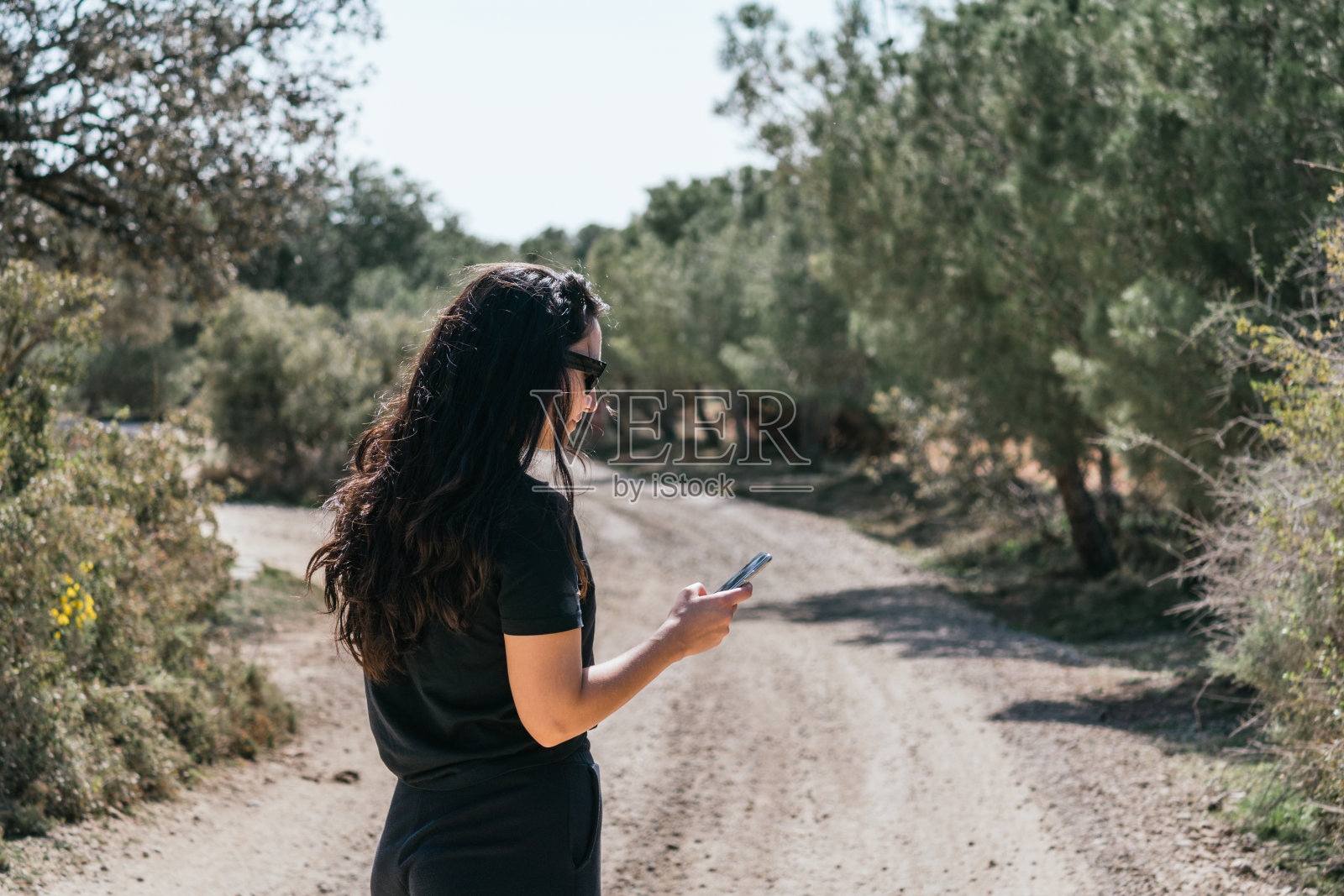 一位女旅行者在乡间散步时看着她的手机照片摄影图片
