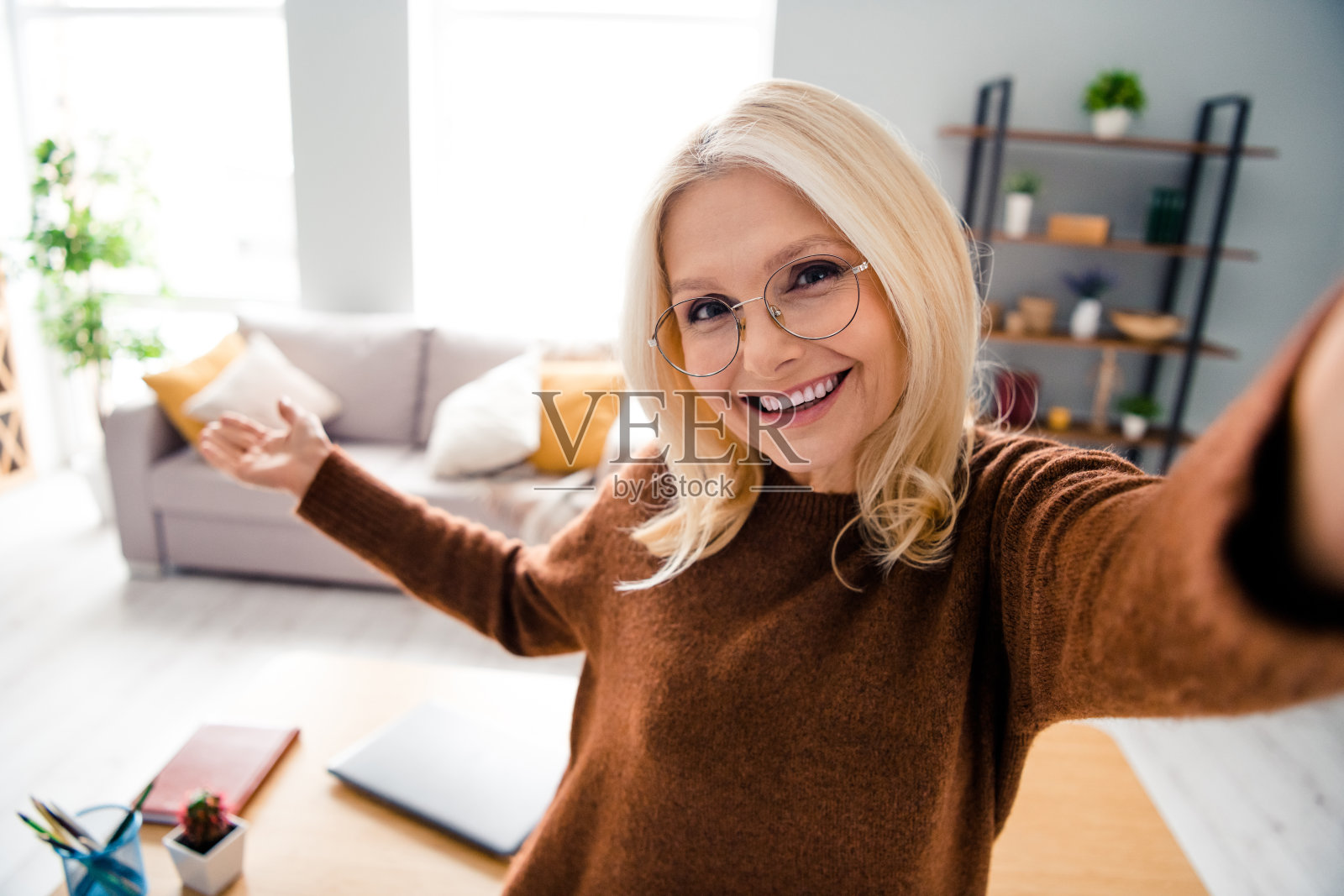 好心情的奶奶高兴地展示她的新工作室公寓，室内看起来像家庭办公室，内部有现代阁楼照片摄影图片