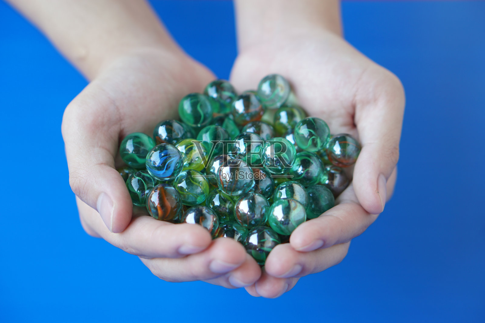 近距离的手拿着弹珠球，通常由玻璃、粘土、钢、塑料或玛瑙制成的小球形物体。的概念。物件可用作玩游戏的玩具或DIY工艺装饰。照片摄影图片