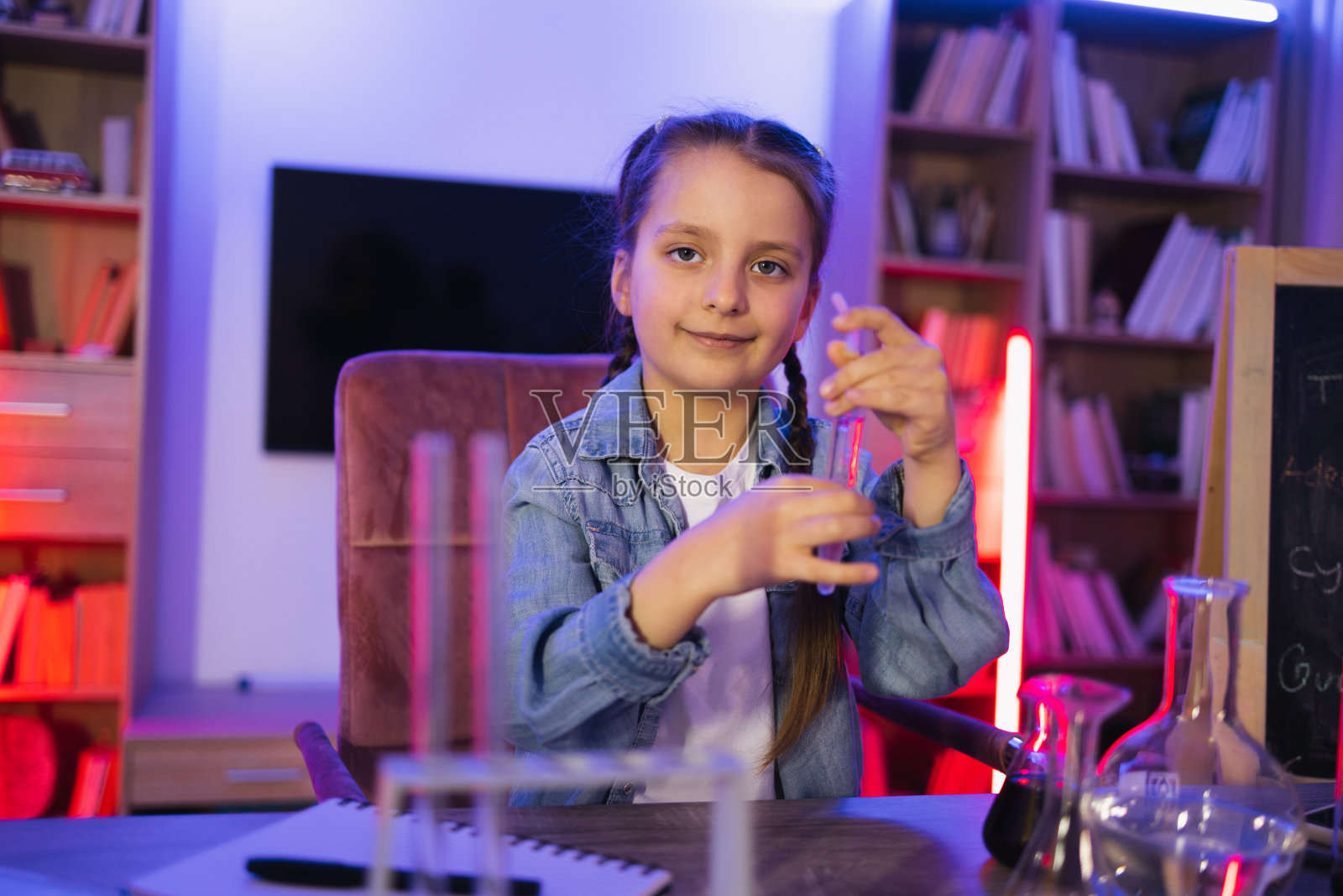 专心做化学实验的女孩在客厅看着试管。照片摄影图片