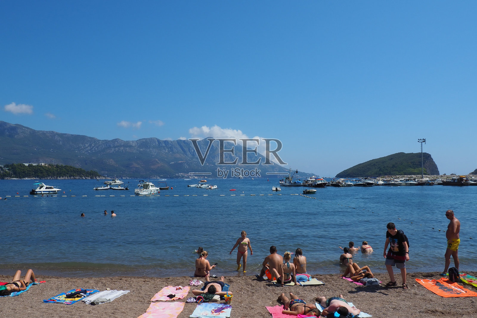 鹅卵石混凝土公共海滩亚得里亚海地中海。沙滩伞和毛巾。人们放松，游泳，享受日光浴。旅游业务。女人和男人在放暑假照片摄影图片