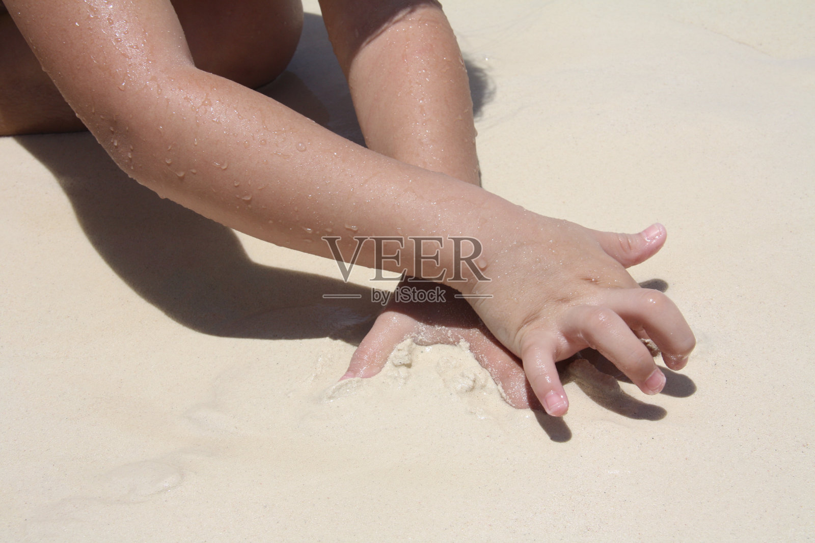 女孩的手在沙滩上玩沙子。照片摄影图片