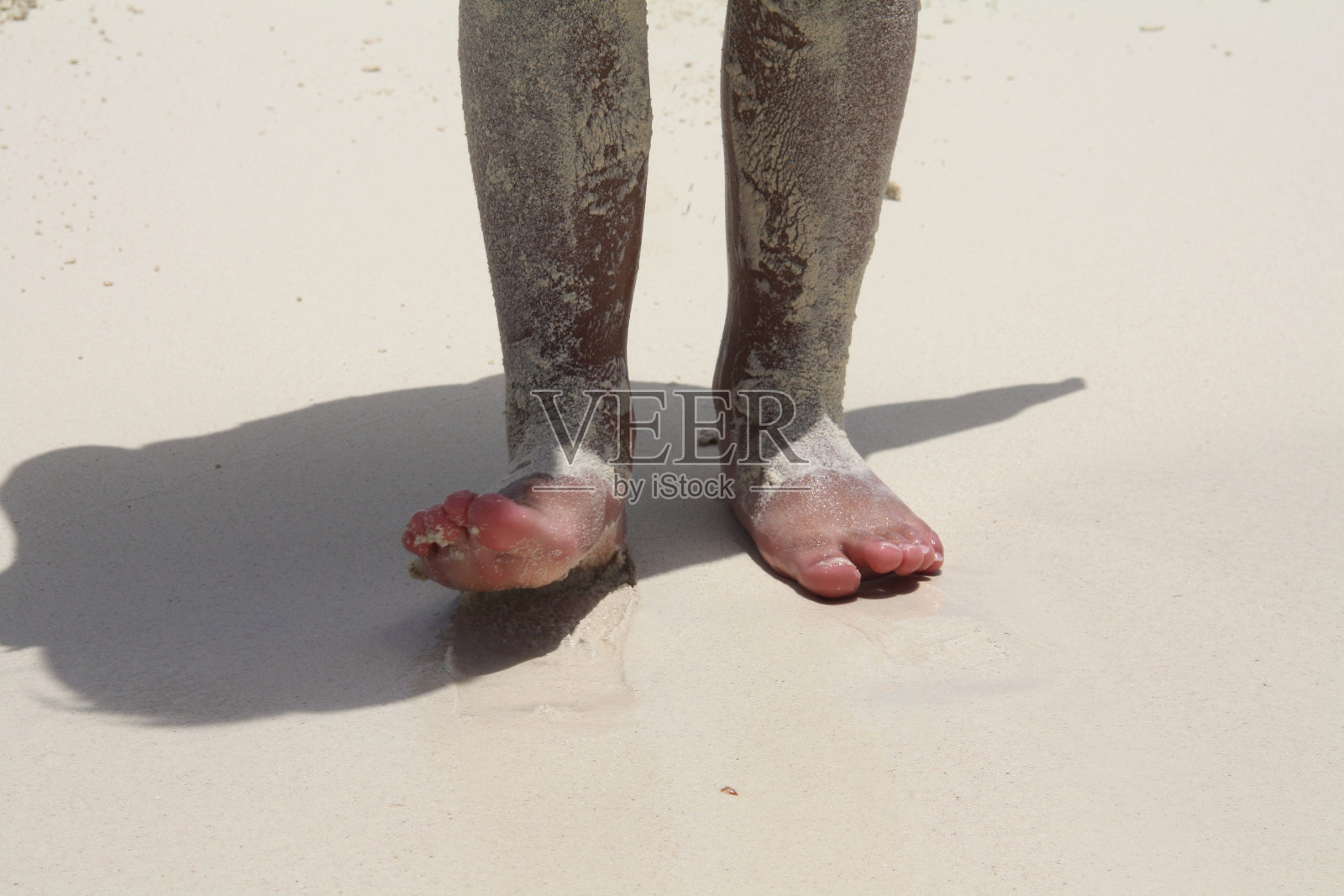 孩子的脚上满是沙滩上的沙子。照片摄影图片