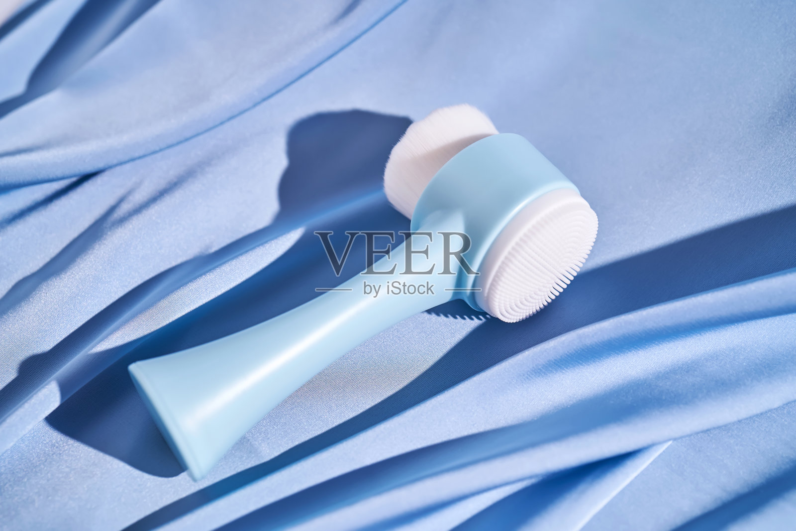 蓝色刷按摩器的脸在蓝色丝绸的背景。照片摄影图片