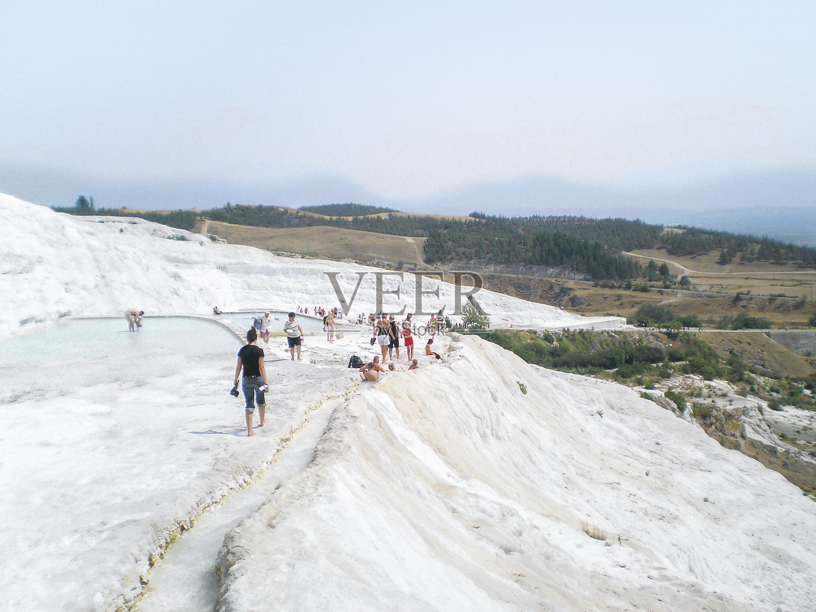 在土耳其西南部的德尼兹利省，游客们在Pamukkale温泉中沐浴，层层叠叠的梯田浴池装饰着雪白的方解石钟乳石。照片摄影图片