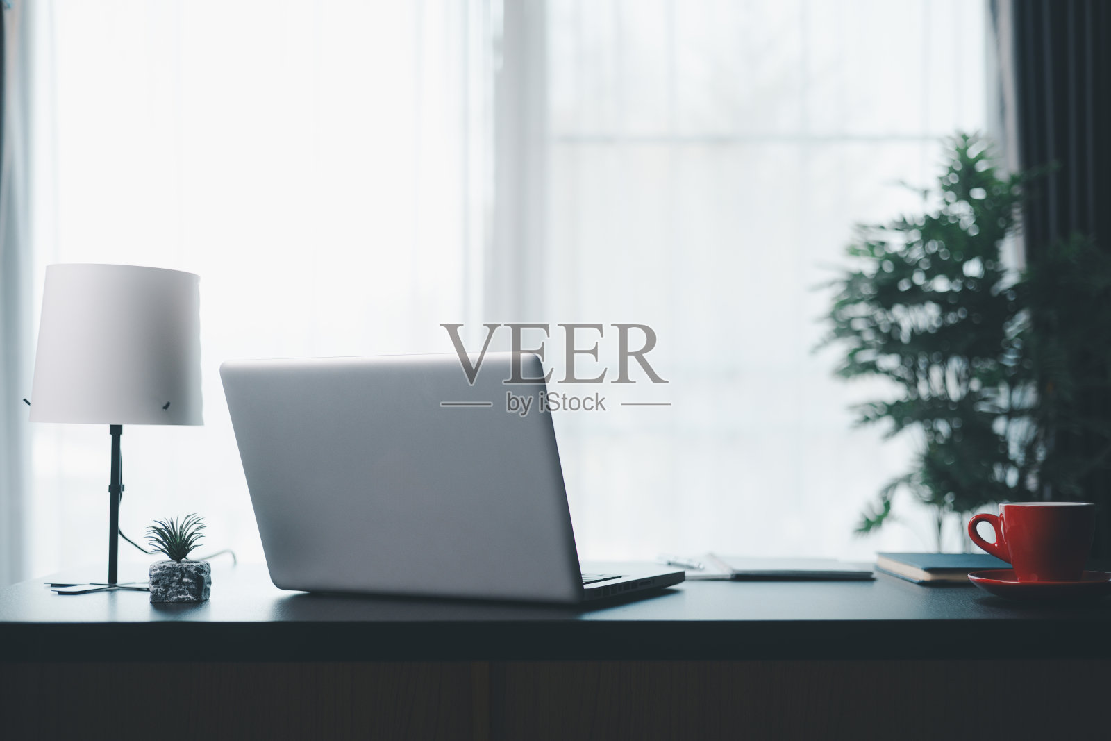 办公场所，笔记本电脑和智能手机放在木桌上。工作空间，台式电脑，办公用品，室内植物和办公室书籍。案头工作概念。在办公室舒适的工作台。照片摄影图片