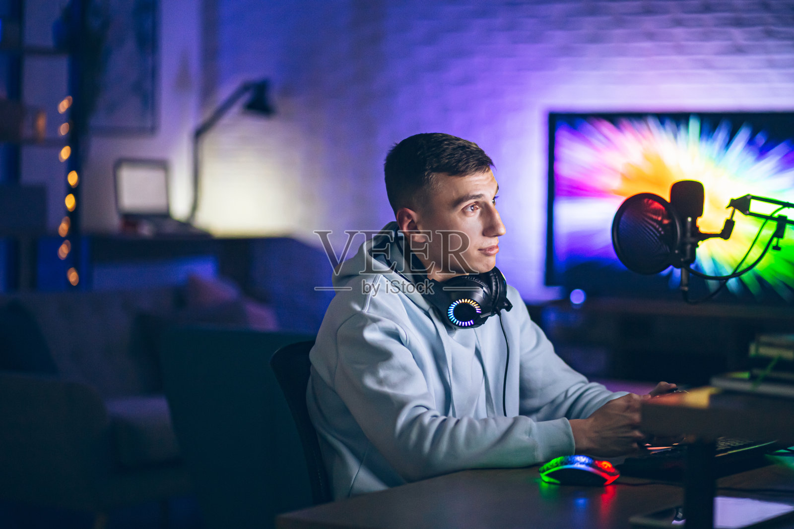 电子竞技玩家在房间里直播游戏，背景是霓虹灯照片摄影图片