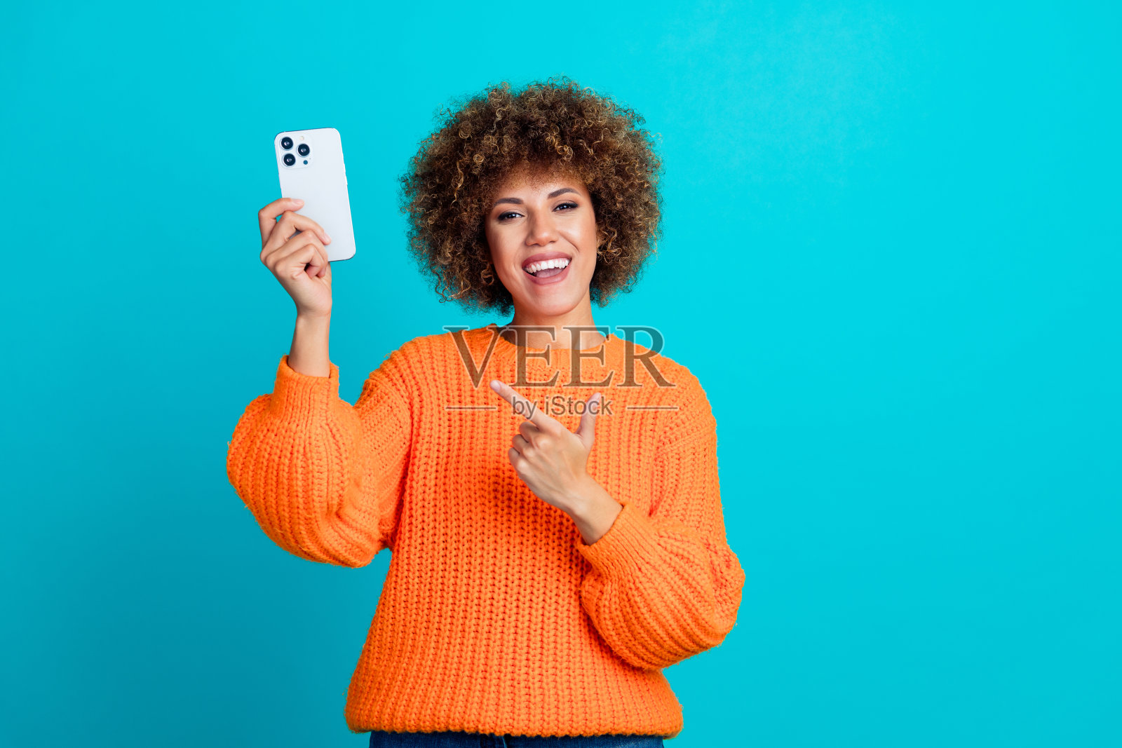 照片华丽迷人的拉丁女孩穿着时尚的橙色衣服，展示了新奇的凉爽提供孤立的蓝色背景照片摄影图片